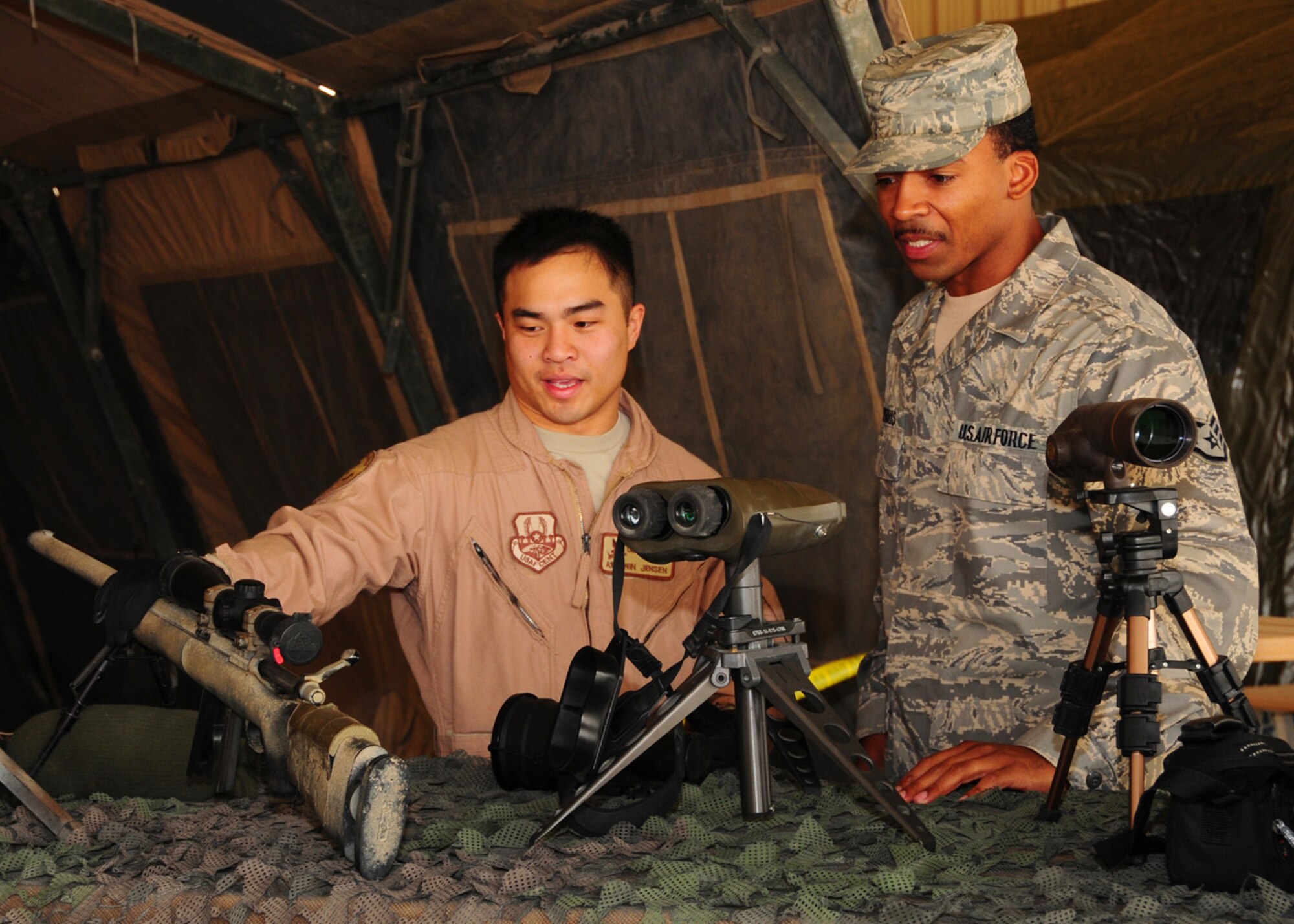 SOUTHWEST ASIA -- Airman 1st Class Win Jensen, 386th Expeditionary Security Forces Squadron, shows Staff Sgt. Terrell Morris, 386th Air Expeditionary Wing protocol, the types of weapons and equipment used by Advanced Designated Marksmen at an air base in Southwest Asia, May 11. The ADM's role is to supply rapid accurate fire on enemy targets with a highly-accurate, semiautomatic rifle equipped with a telescopic sight. Airman Jensen is currently deployed from Patrick Air Force Base, Fla., and is originally from Tampa, Fla. Sergeant Morris is currently deployed from Lackland Air Force Base, VA and is originally from Chicago. (U.S. Air Force photo/ Senior Airman Courtney Richardson)