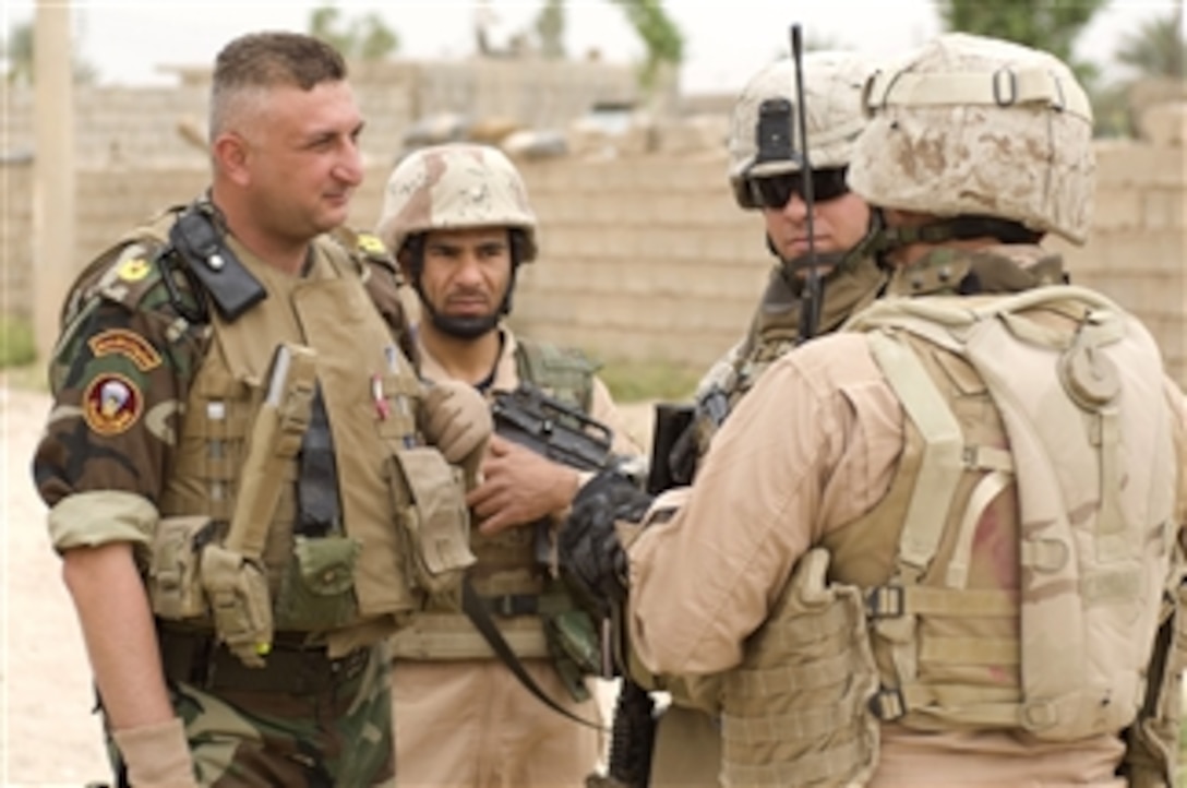 An Iraqi officer from 2nd Battalion, 2nd Brigade, 1st Iraqi Army Infantry Division speaks with U.S. Marine Corps 1st Lt. Austin Hill (2nd from right) with U.S. Marine Corps Military Transition Team 0120 during an Iraqi clearing operation in Al Asreya, Iraq, on May 5, 2009.  