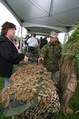 Staff Sgt. James Guerra, 35, scout sniper platoon sergeant for Chicago-based 2nd Battalion, 24th Marine Regiment, shows Robin Pokoyoway, 50, a sniper guille suit. Marines from various units assisted in a static display at Sears Holdings May 13 as part of Marine Week Chicago. People in attendance were able to walk through different vehicles used by Marines. They were also allowed to handle weapons used by Marines.