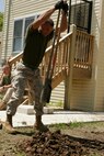 Sgt. Jeremy Owens, an armored vehicle mechanic with California-based 3rd Assault Amphibian Battalion, 1st Marine Division, punctures a hole in the earth to make way for the bases of a chain-linked fence as part of a project with the Windy City Habitat for Humanity in Chicago’s South Side.