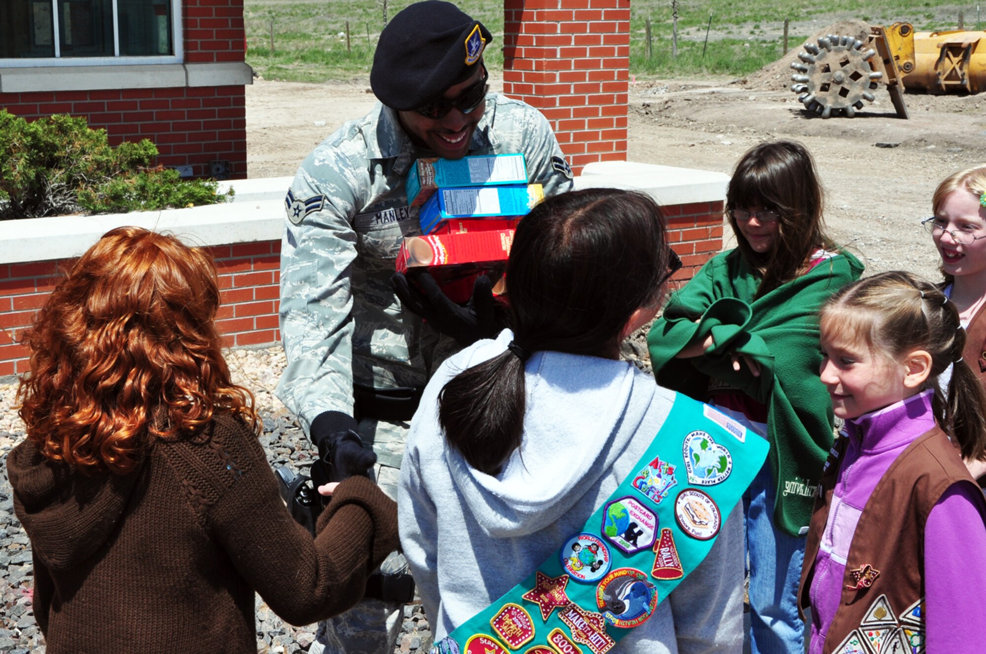 Airman 1st Class Enrique Manley, 90th Security Forces Squadron, receives several boxes of cookies from Girl Scouts from Troop 160 out of Fort Collins, Colo., at Gate 2 Saturday. The troop dropped off 12 dozen boxes of assorted cookies for the Warren Airmen. The cookies will be distributed through group and squadron first sergeants (U.S. Air Force Photo/Staff Sgt. Chad Thompson).