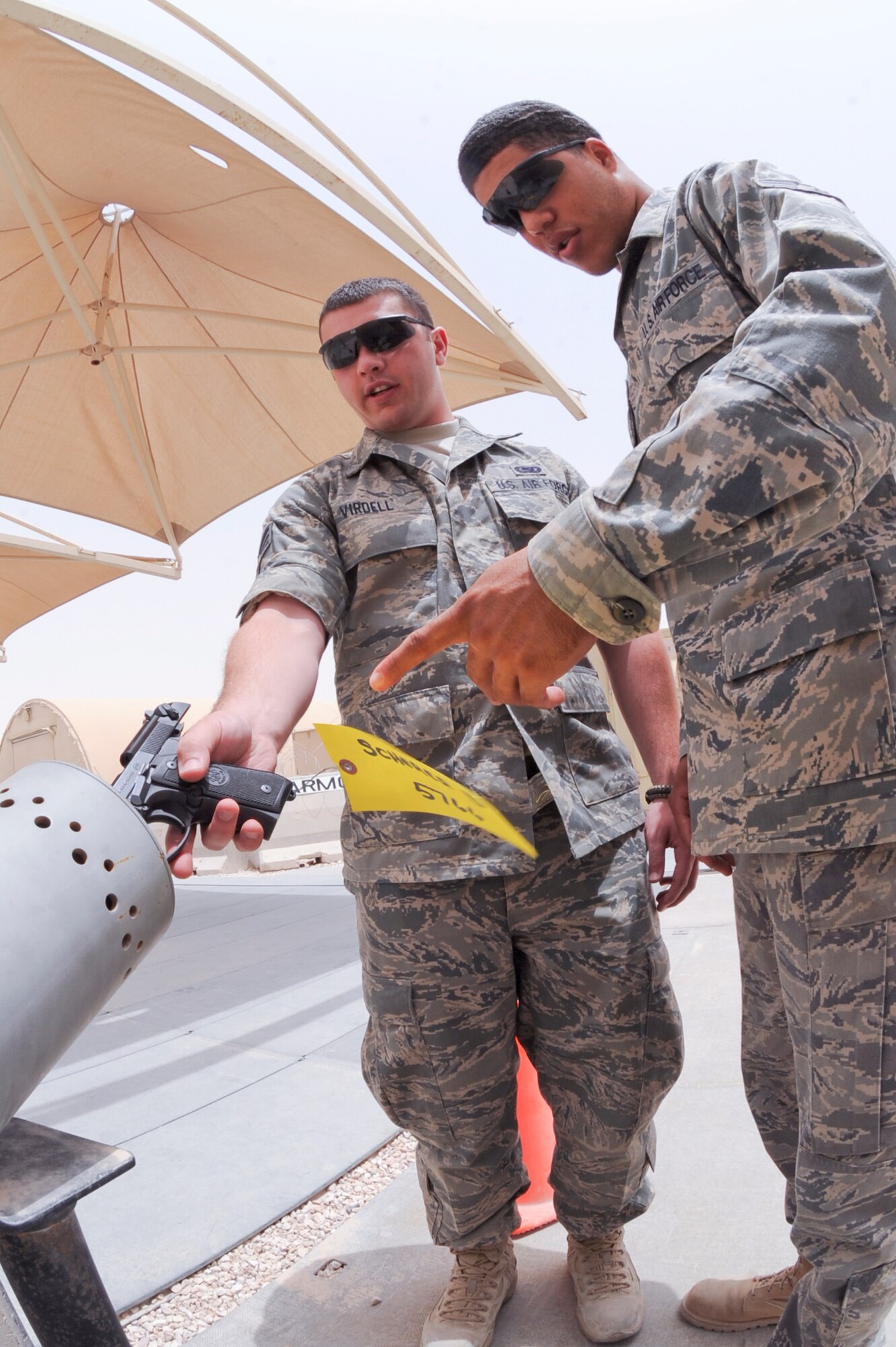 Airman 1st Class Jonathan Kelley, a supply journeyman for the 379th Logistic Readiness Squadron, shows Senior Airman Brett Virdell, 379th Expeditionary Logistic Readiness Squadron, how to properly clear a 9mm pistol here, May 14, 2009, in an undisclosed location in Southwest Asia.  Airman Kelley and fellow armory personnel handle and safeguard up to 20,000 weapons belonging to transient personnel during rotational surges.  Airman Kelley is native to Crenshaw, Calif. and is deployed from Ellsworth Air Force Base, S.D. while Airman Virdell hails from Tulsa, Okla. and is deployed from Buckely Air Force Base, Colo., both in support of Operations Iraqi and Enduring Freedom and Combined Joint Task Force - Horn of Africa. (U.S. Air Force Photo by Staff Sgt. Joshua Garcia/released)