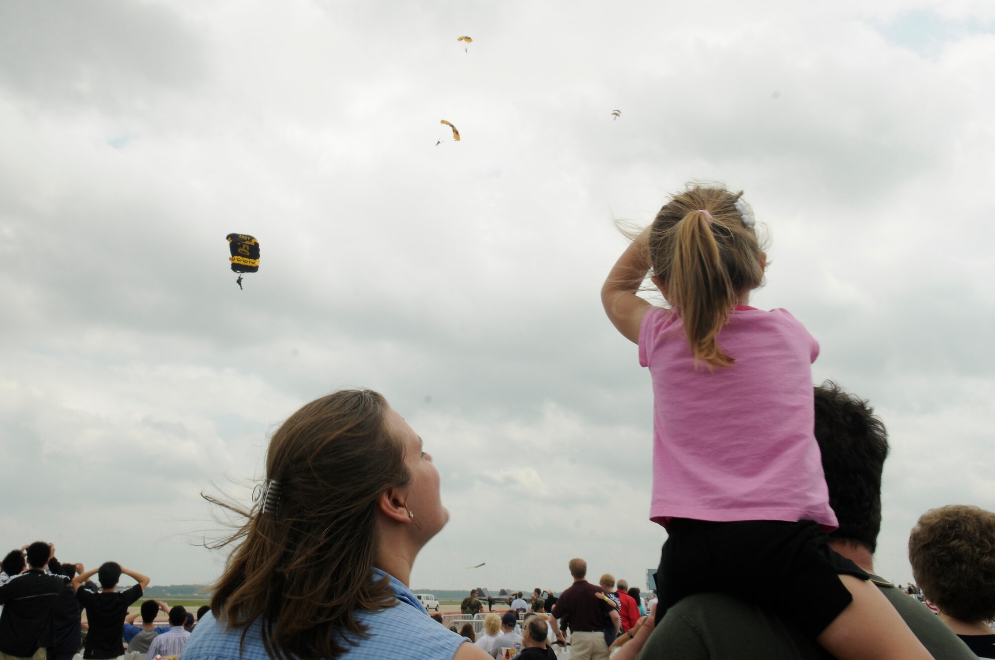 Madison Madariaga sits on top of her dad Paul Madariaga's shoulders as the U.S. Army's Golden Knights parachute to an 18 inch drop zone during the 2009 Joint Service Open House May 16 on Andrews Air Force Base, Md. JSOH celebrates military history while showcasing the future capabilities of the world's finest military force. (U.S. Air Force photo by Staff Sgt. Dan DeCook)