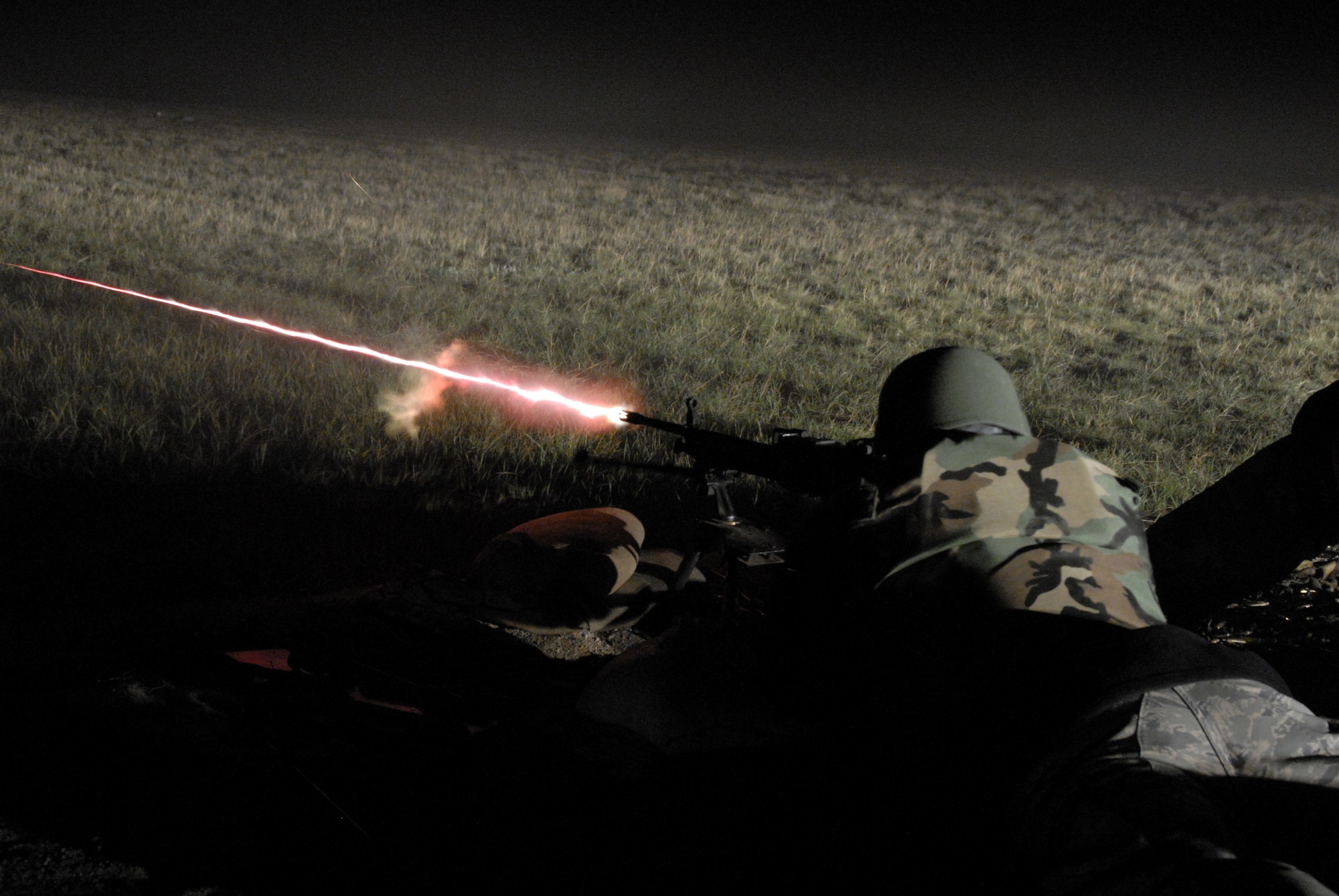 Under the illumination of flares, Security Forces from the 185th Air Refueling Wing, Sioux City, Iowa operate the M-240 and M-249 machineguns during night fire qualification at Fort Harrison, Montana on 13 May 2009.  Tracer rounds aide gunners by allowing him or her to “walk” the fire onto the pop up targets. (US photo by TSgt Brian Cox)