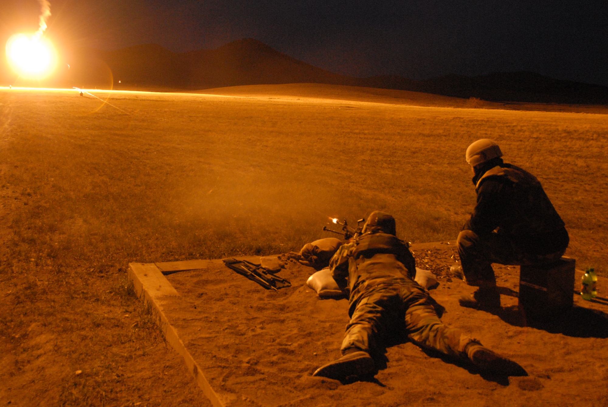 Under the illumination of flares, Security Forces from the 185th Air Refueling Wing, Sioux City, Iowa operate the M-240 and M-249 machineguns during night fire qualification at Fort Harrison, Montana on 13 May 2009.  Tracer rounds aide gunners by allowing him or her to “walk” the fire onto the pop up targets. (US photo by TSgt Brian Cox)