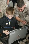 Maj. Sharif Sokkary, Air Officer at the Marine Corps war fighting lab, gives directions to Zachary McPherson, 8, on how to use the deployable virtual training environment May 15. McPherson was acting as a helicopter pilot and destroying targets on the ground.