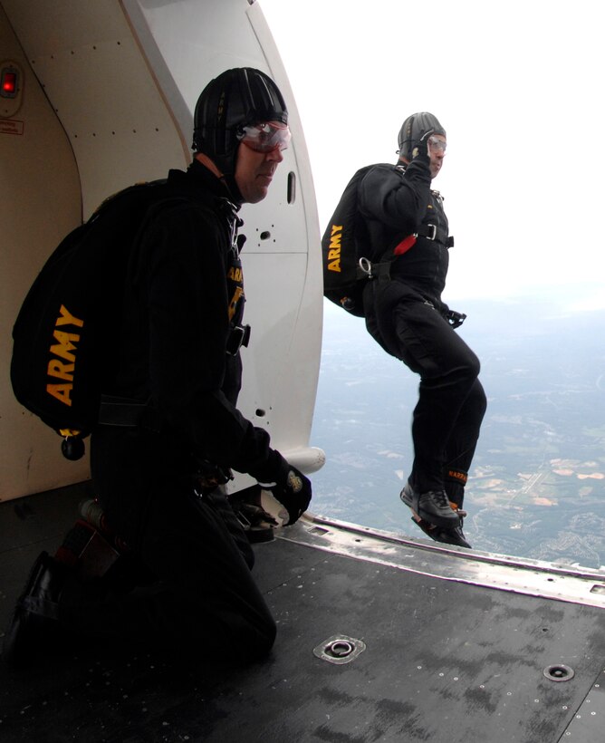 Members of the U.S. Army Golden Knights Black demonstration team jumps out of a C-31A Troopsh during the Joint Service Open House May 17, Andrews Air Force Base, Md. The first jumper for the Golden Knight’s narrates the rest of the demonstration for the team. (U.S. Air Force photo by Airmen First Class Melissa V. Rodrigues)