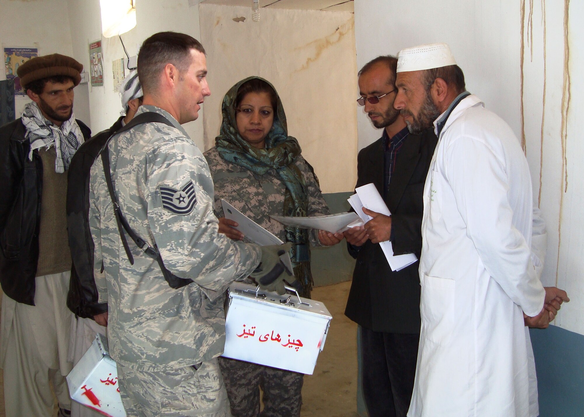 During a visit to the Peshgor Clinic in Khenj District, Air Force Tech. Sgt. James Bailey, a Panjshir Provincial Reconstruction Team medic, provides pharmacist Mohammad Yagub, right, and Ghulam Maiudin, a vaccinator, with containers to properly dispose of needles and other biohazardous materials.  (U.S. Air Force photo by Maj. Valerie Trump)                               