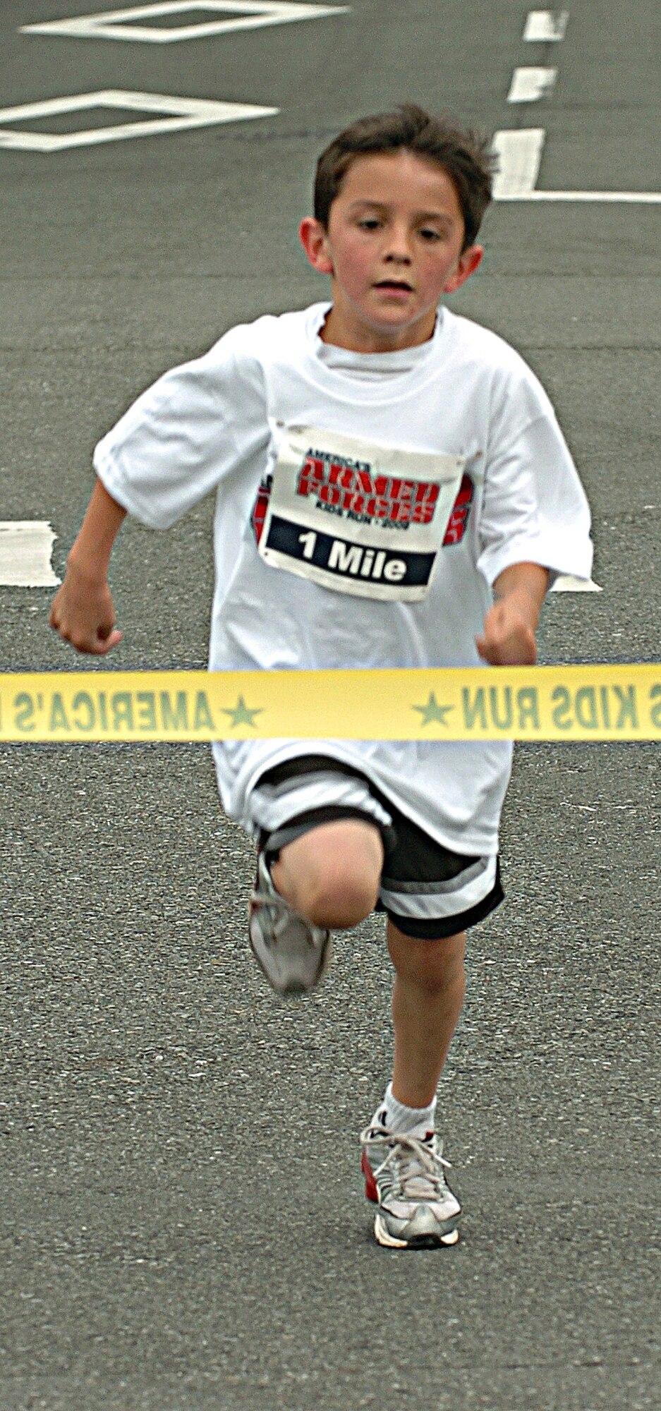 YOKOTA AIR BASE, Japan -- John Fuentes, son of Tech. Sgt. Malcolm Fuentes, 373rd Training Squadron, Det. 15, crosses the finish line first in the 7-8-year-old division at the Armed Forces Kids Run 2009 May 16 on the base's west side. More than 100 children took part in the 24th anniversary of the run held at military installations worldwide. It's designed to give children a fun and safe way to exercise. (U.S. Air Force photo/Master Sgt. Matt Summers)