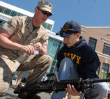 Lance Cpl. Nicohlas D. Wlodaski, machine gunner, 2nd Battlion 24th Marines, Chicago, watches as Mike Fullerton, freshman, Wheaton Warrenville South High School, Wheaton, Ill., picks up a M240B medium machine gun at the weapons diplay at Navy Pier, Chicago, during Marine Week May 17.