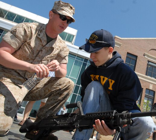Lance Cpl. Nicohlas D. Wlodaski, machine gunner, 2nd Battlion 24th Marines, Chicago, watches as Mike Fullerton, freshman, Wheaton Warrenville South High School, Wheaton, Ill., picks up a M240B medium machine gun at the weapons diplay at Navy Pier, Chicago, during Marine Week May 17.