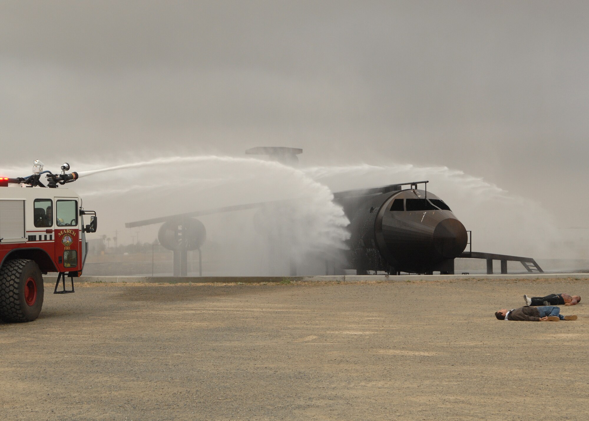 A base fire truck shoots water onto a mock aircraft which simulated a crashed C-17. In front of the aircraft, two casualties from the wreckage await triage as part of the MARE or Major Accident Response Exercise. The MARE tested March ARB, City and County of Riverside, City of Moreno Valley, City of Perris, Cal Fire and American Medical Response’s ability to respond and recover from an aircraft accident involving mass casualties. (U.S. Air Force photo by SSgt Stephen Schester)