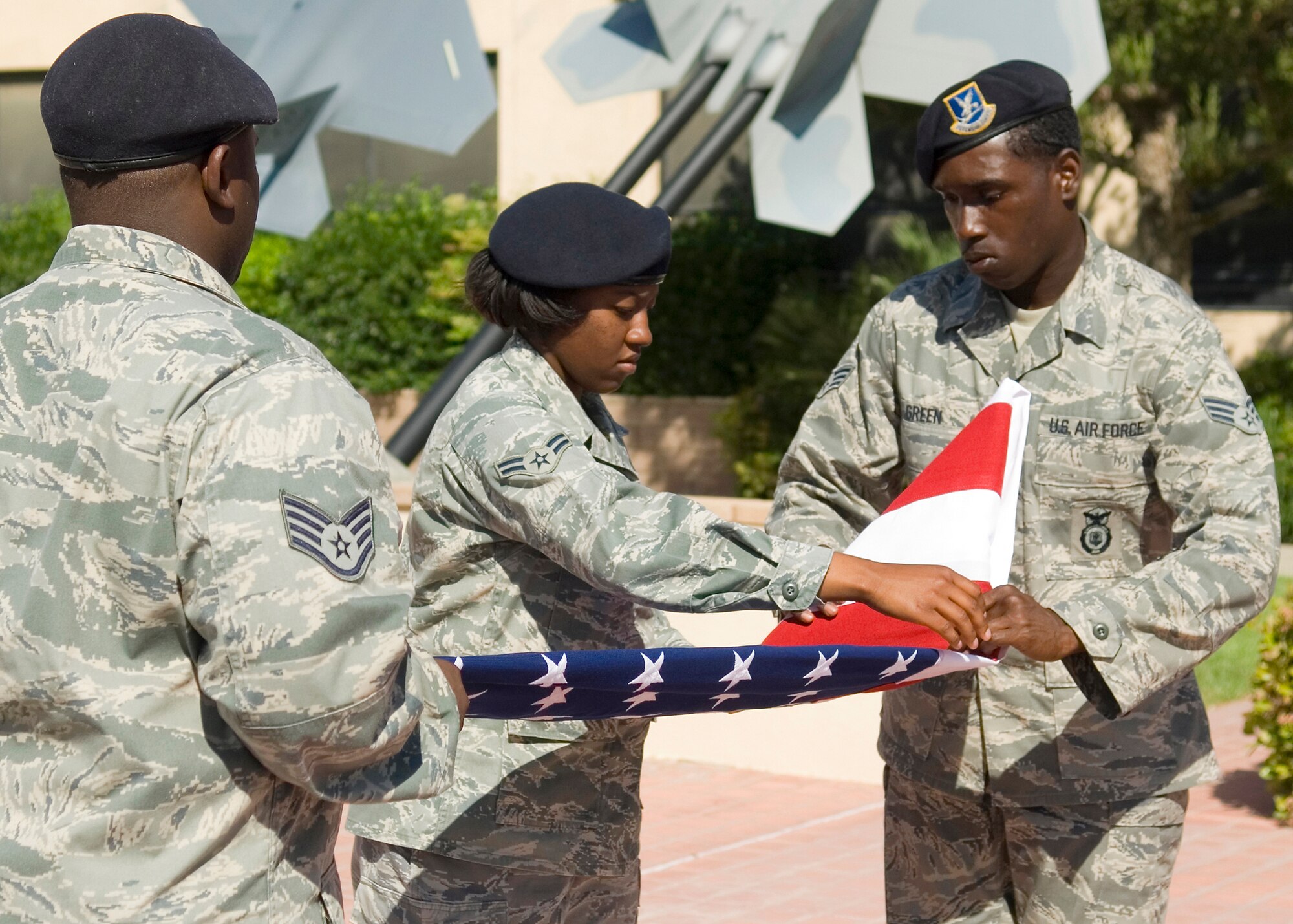 Staff Sgt. Kodi Jackson (left), Airman 1st Class Kimberly Presley (center) and Senior Airman Armand Green, 95th Security Forces Squadron honor guard members, fold the flag during a retreat ceremony at the Air Force Flight Test Center Headquarters May 15. The 95th SFS hosted the event. (U.S. Air Force photo/Mike Cassidy)