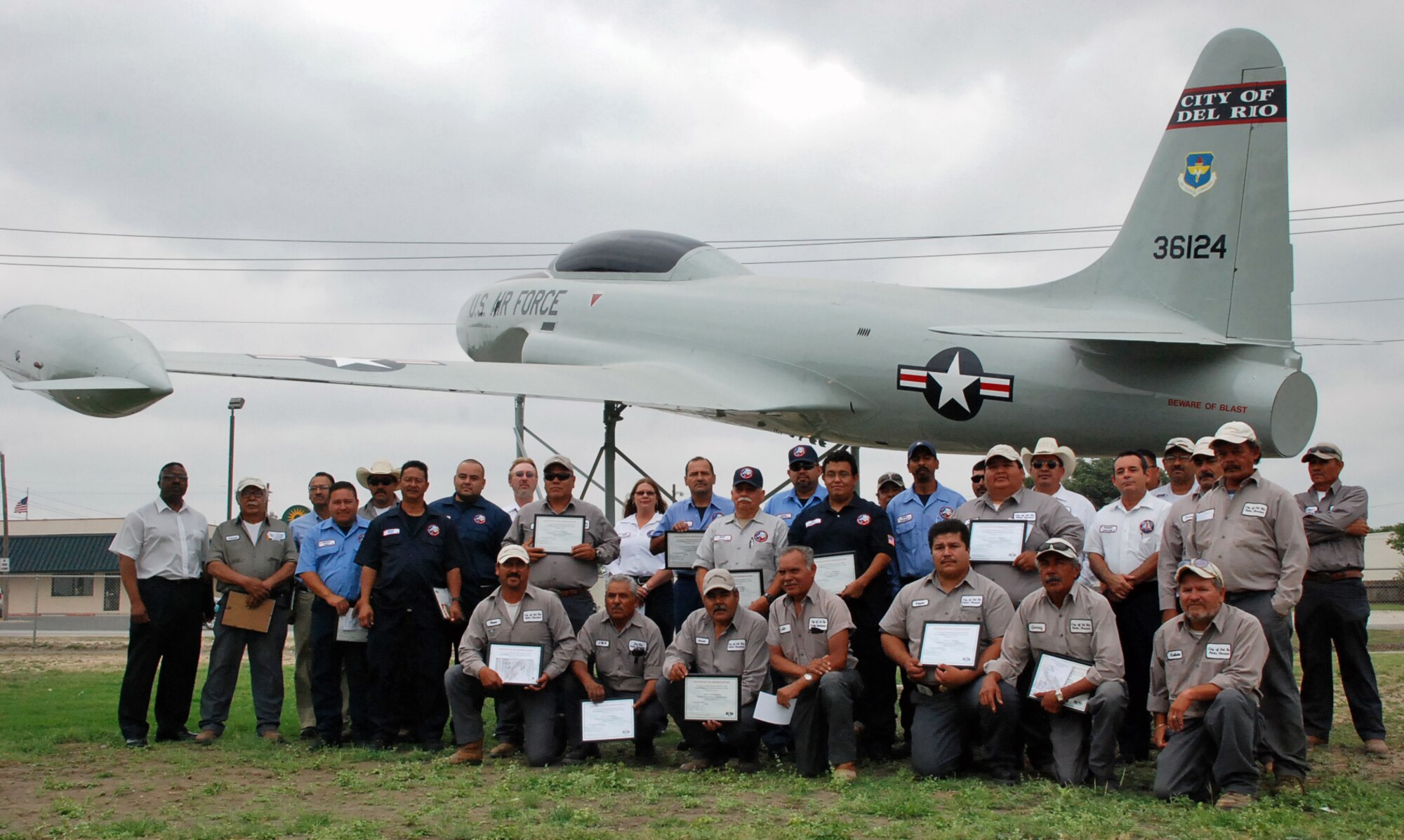 LAUGHLIN AIR FORCE BASE, Texas—Volunteers from Laughlin and Del Rio gather under the T-33 Shooting Star during a rededication ceremony for the static at the Del Rio Civic Center May 14.  The ceremony was held to thank the volunteers who spent more than two weeks stripping, sanding and repainting the aircraft.  The aircraft was used at Laughlin to help train more than 1,200 student pilots from 1953 through 1957 and again from 1960 through 1965. (U.S. Air Force photo by 1st Lt. Courtney Kippenberger)         