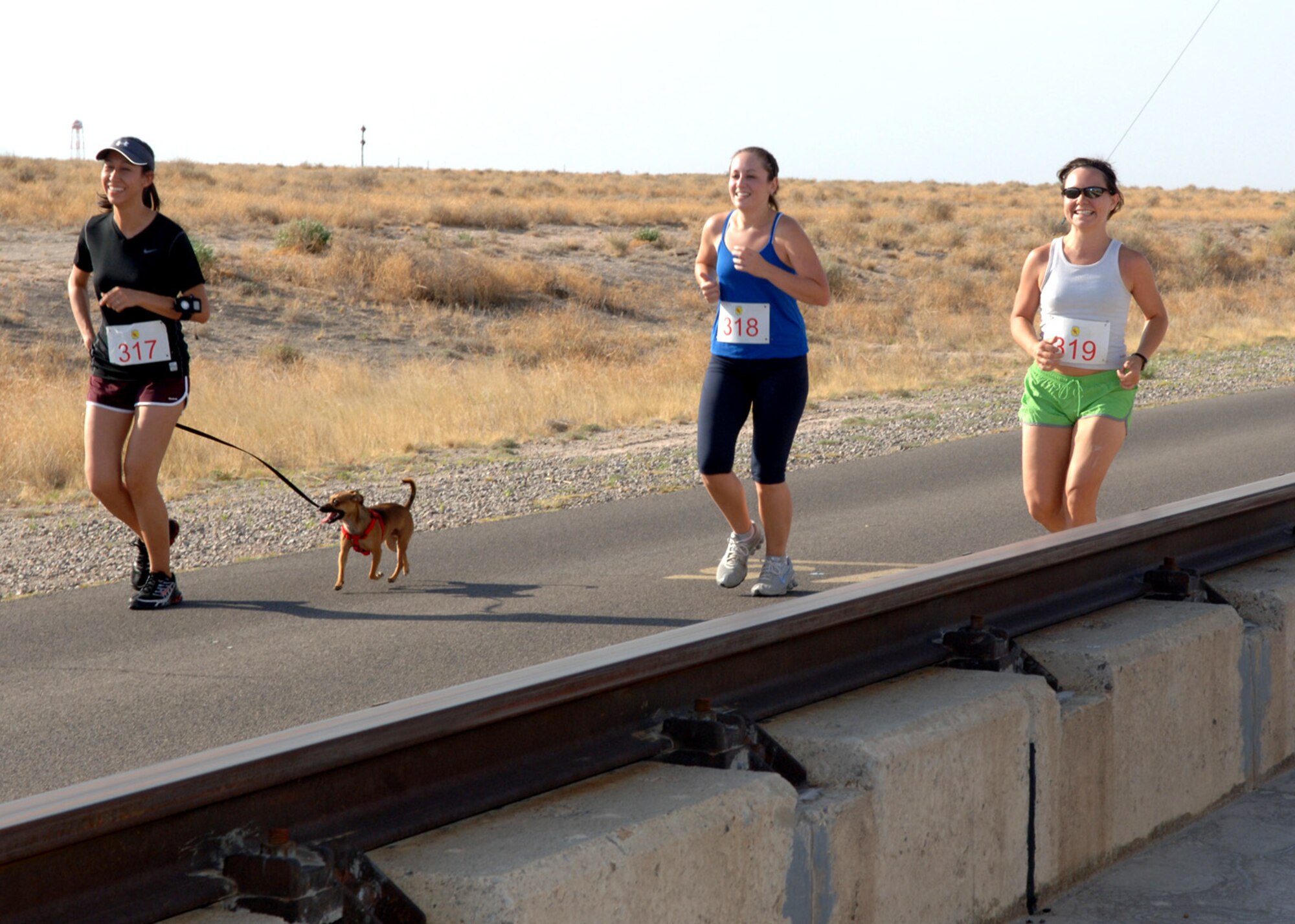 Yuki Cole, 746th Test Squadron runs with her Chihuahua, Rusty, and two military spouse runners, Carolyn Small and Christine Rondeau, during the Mach 10K Run at Holloman Air Force Base, N.M., May 15. The annual Mach 10K run was a base community event that promoted awareness of the Holloman High Speed Test Track. (U.S. Air Force photo/ Airman 1st Class Veronica Stamps)