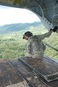 Army Sgt. Michael Marquis, 1st Battalion, 228th Aviation Regiment, keeps a watchful eye out the rear of his aircraft during flight.  He is looking for any hazards that might come within range of the 32,000-pound aircraft.  Sergeant Marquis is a CH-47D Chinook crew chief assigned to the Joint Task Force-Bravo Chinook crew in Nicaragua this week to fly medics and equiment to two remote villages for medical readiness exercises.  (U.S. Air Force photo/Tech. Sgt. Rebecca Danét)