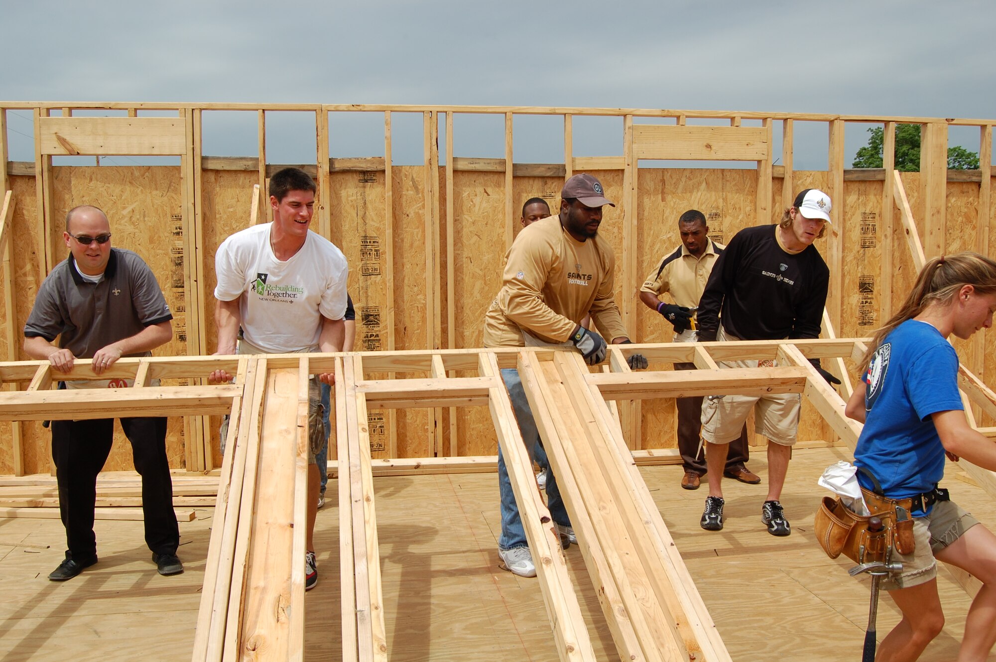 Members of the New Orleans Saints football team lift a wall frame into place as part of a Habitat for Humanity project in New Orleans. Recruiters from the 331st Recruiting Squadron teamed up with the Saints to help construct the house in Musicians’ Village located in the Lower 9th Ward. (Courtesy photo)