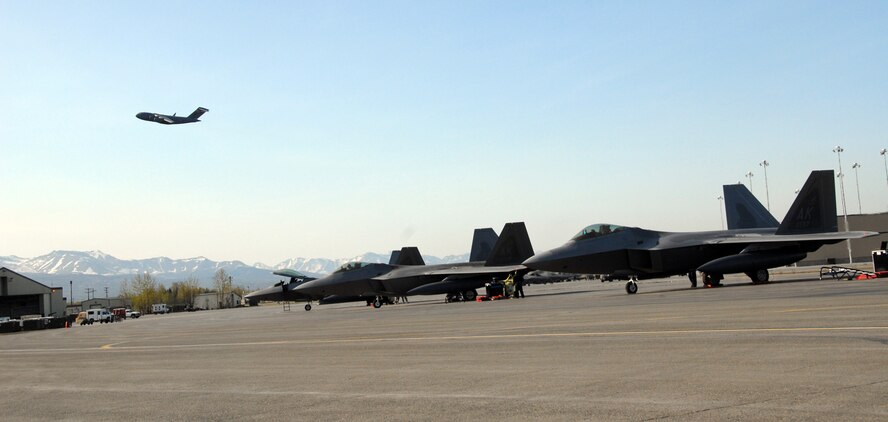 ELMENDORF AIR FORCE BASE, Alaska –Crew chiefs and fighter pilots prepare 12 F-22A Raptors for departure to Andersen Air Force Base, Guam, as a C-17 flies over May 12. Two of the 12 pilots are from Air Force Reserve Command’s 477th Fighter Group. The Air Force regularly deploys additional forces throughout the Western Pacific as part of its continuing force posture adjustments to address worldwide requirements. (U.S. Air Force photo/Staff Sgt. Andrea Knudson)