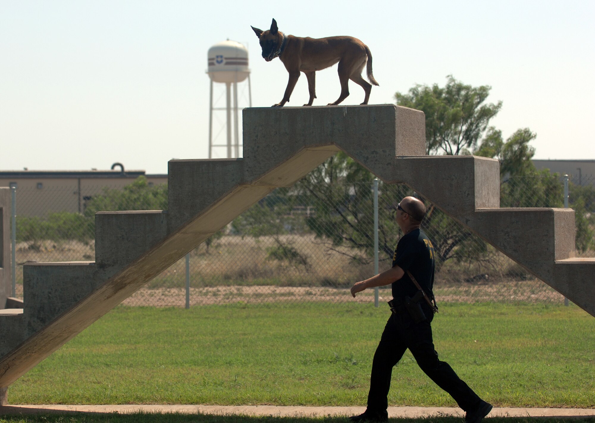 On top of a staircase obstacle during the K-9 competition is San Angelo Police Department K-9 Pepper, closely watched by her handler, Police Sgt. David Egger. Sergeant Egger and Pepper placed first in the Patrol Apprehension event of the K-9 competition. (U.S. Air Force photo by Tech. Sgt. John Barton)