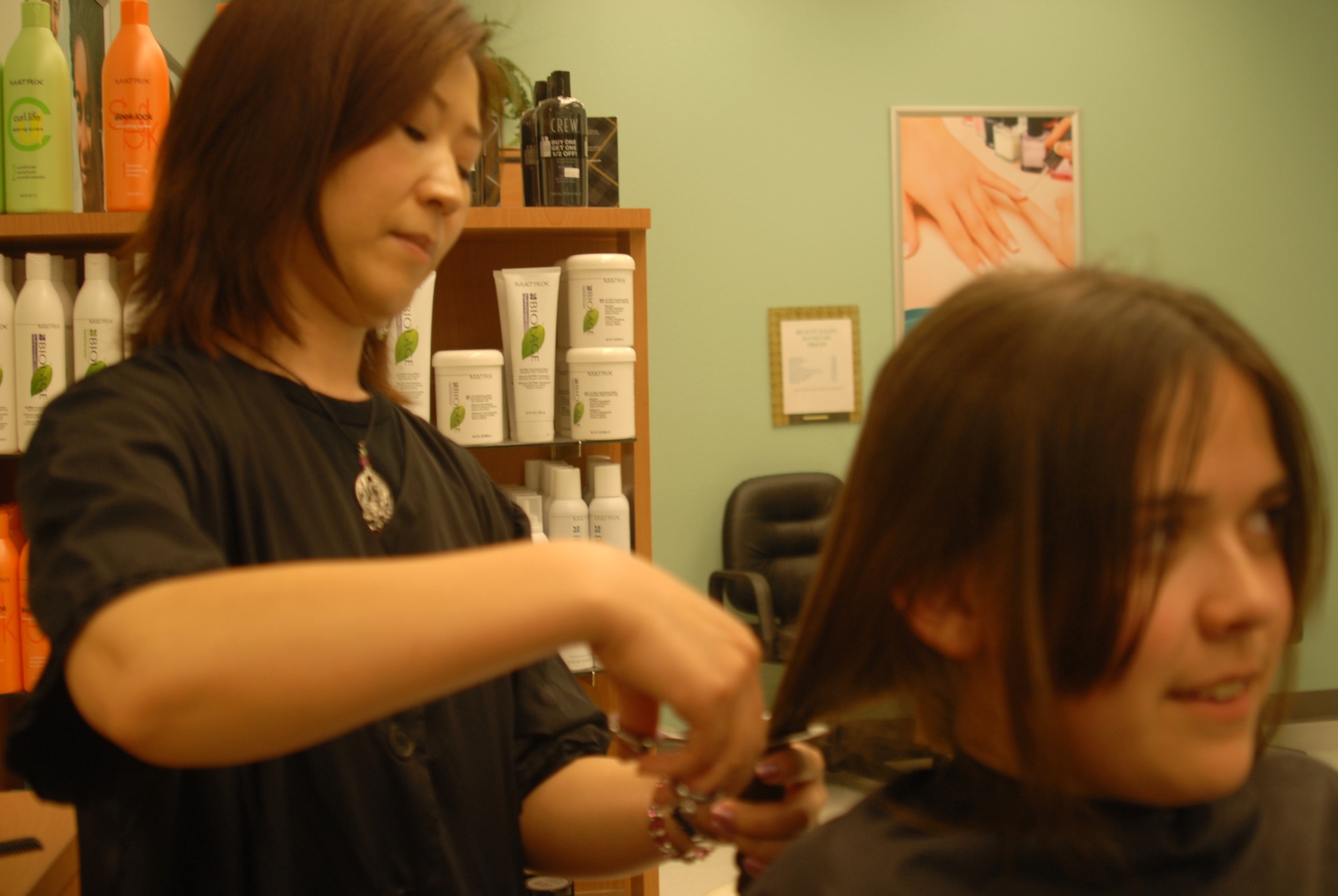 Rae Park cuts off 10 inches of Amanda Medina's hair at the BX salon.  Amanda, an Air Force dependent, donated two 10-inch ponytails to Locks of Love. (U.S. Air Force photo by Airman 1st Class Anne Gathua)