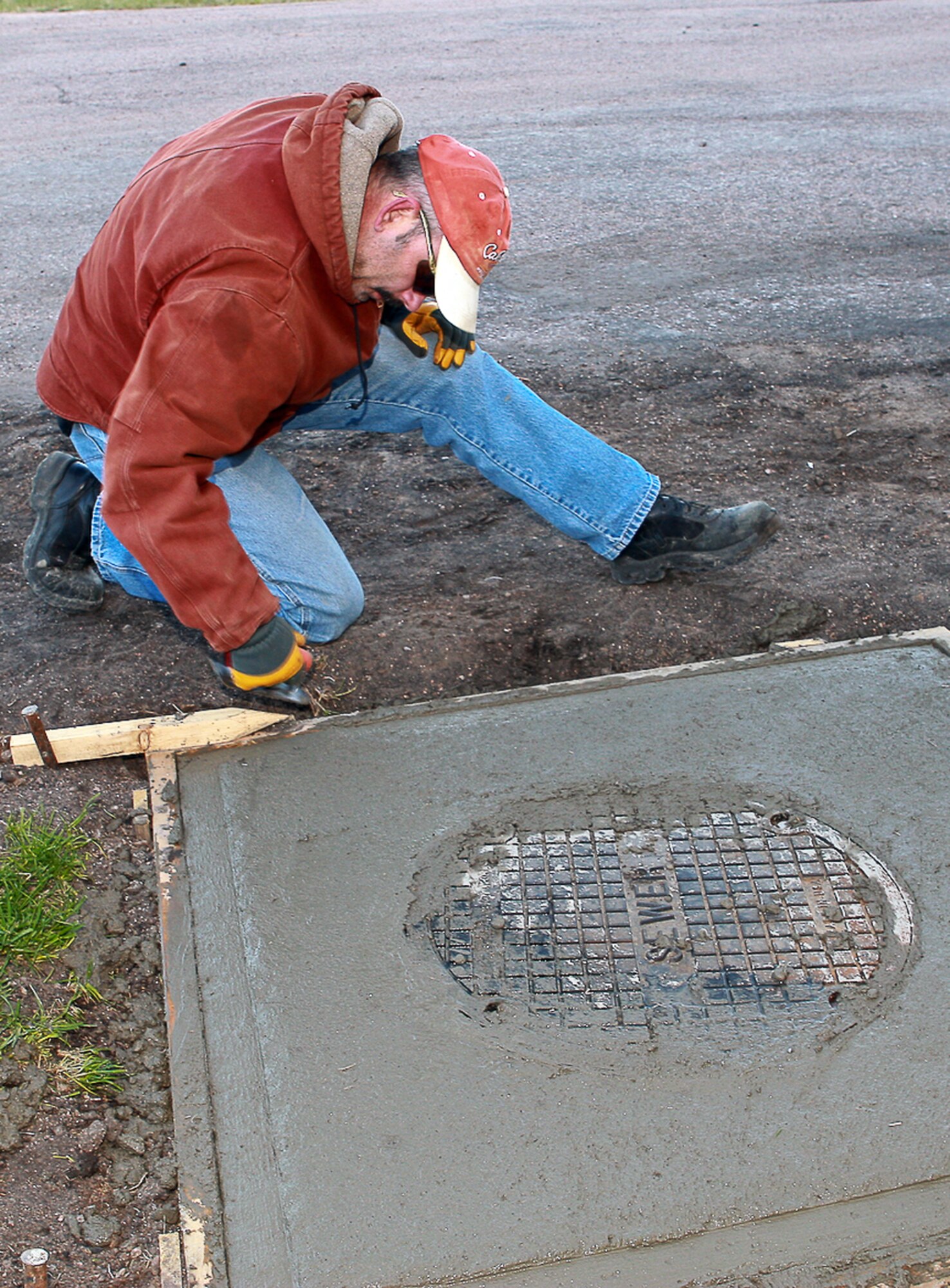 James Munsterman, 90th CES, creates an edge on freshly poured concrete for a sewer hole during the project.