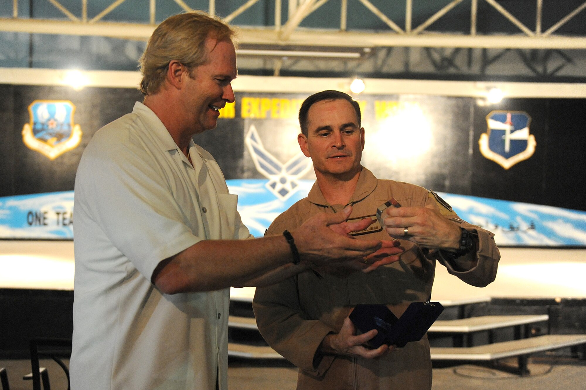 SOUTHWEST ASIA - Brig. Gen. H.D. Polumbo Jr., 380th Air Expeditionary Wing, commander, presents Mr. Dan Clark, inspirational speaker and author, with a crystal paper weight of the 380th AEW emblem, May 11 at an undisclosed location in Southwest Asia. Mr. Clark's spoke to Airmen and encouraged them to do their best and work hard in all aspects of life and take the hard work done here home with them. (U.S. Air Force photo by Senior Airman Brian J. Ellis) (Released)