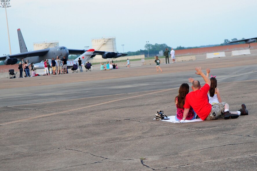 A family of spectators wave to a passing F-15 from the Air Combat Command Strike Eagle Demonstration Team during the twilight portion of the Defenders of Liberty Air Show, May 8. The twilight show was open to Department of Defense identification card holders and their families. (U.S. Air Force photo by Senior Airman Joanna M. Kresge)
