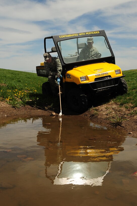 Airman 1st Class Corey Turpin, 28th Civil Engineer Squadron pest management apprentice, samples a pool of water for signs of mosquitoes, while Airman 1st Class Robert Sirvid drives, May 14.  The pest management shop checks all pools of water on base for mosquito larvae to prevent the potential spreading of diseases. (U.S. Air Force photo/Senior Airman Anthony Sanchelli)