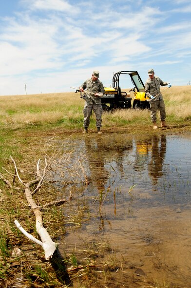 Airmen 1st Class Robert Sirvid (left) and Corey Turpin, 28th Civil Engineer Squadron pest management apprentices, check dippers for signs of mosquito larvae in a pool of water, May 14.  The pest management shop checks all pools of water on base for mosquitoes during the warmer seasons to prevent them from maturing. (U.S. Air Force photo/Senior Airman Anthony Sanchelli)