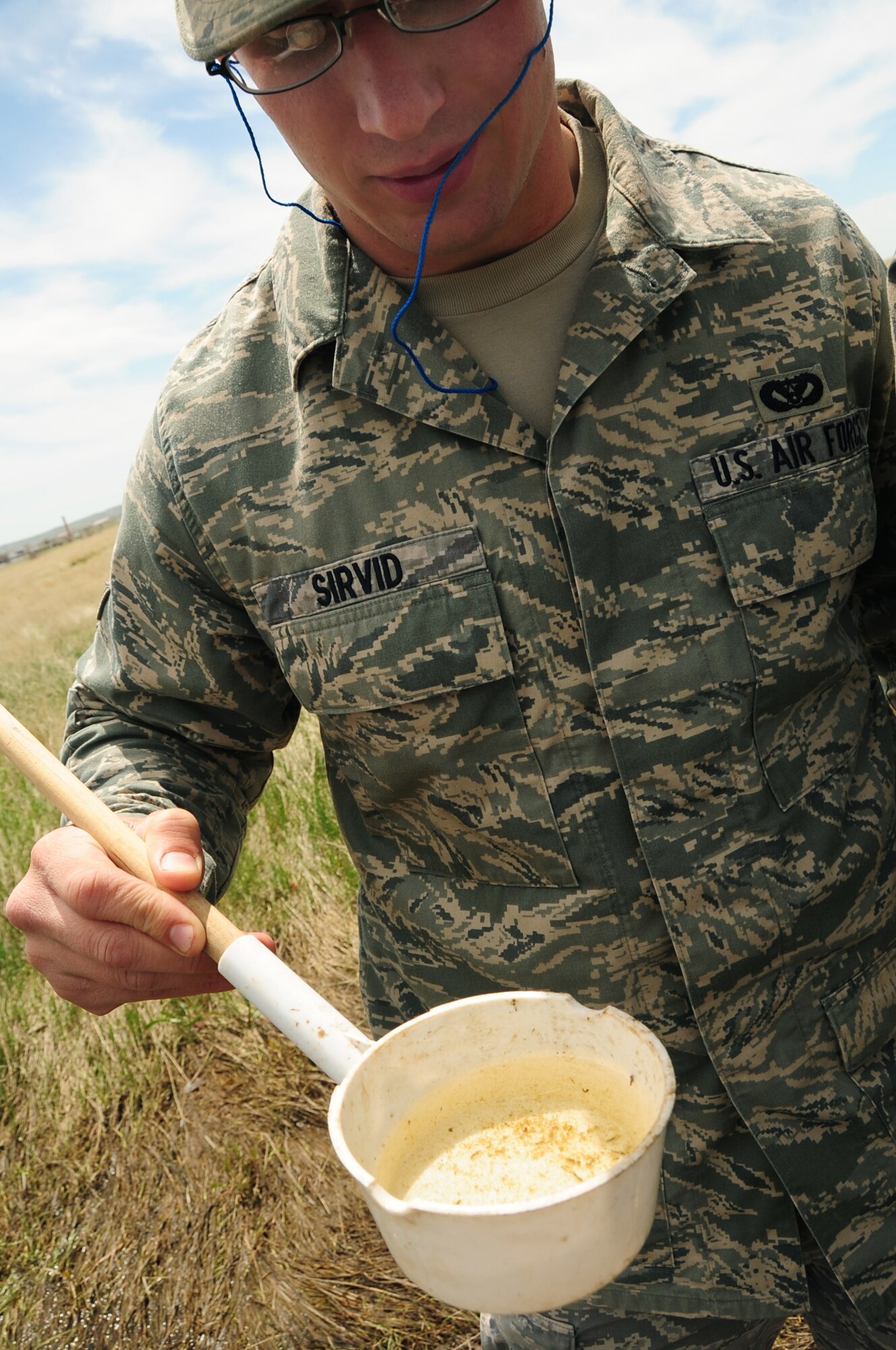 Airman 1st Class Robert Sirvid, 28th Civil Engineer Squadron pest management apprentice, checks a dipper for signs of mosquito larvae, May 14.  The pest management shop checks all pools of water on base for mosquitoes during the warmer seasons to prevent the potential spreading of diseases. (U.S. Air Force photo/Senior Airman Anthony Sanchelli)