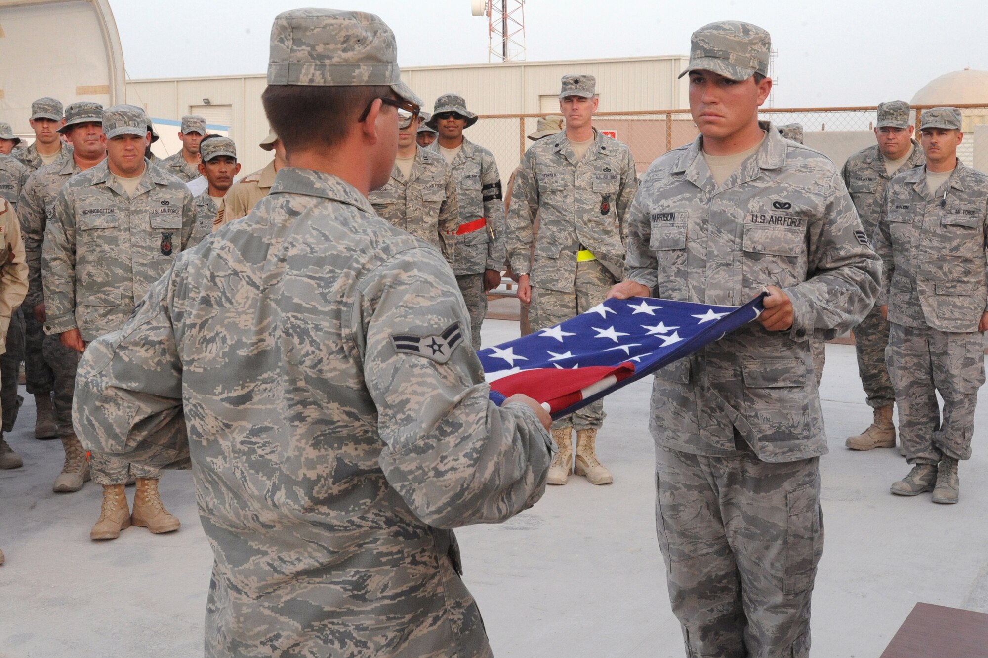 Senior Airman Drew Harrison and Airman 1st Class Robert Fischer, both pavement and equipment operators better known as "dirt boyz", from the 379th Expeditionary Civil Engineer Squadron, fold a flag during the memorial ceremony honoring Master Sgt. Evander "Andy" Andrews here, May 15, 2009 in an undisclosed location in Southwest Asia.  Master Sgt. Andrews was Operation Enduring Freedom's first fatality.  Airman Harrison is native to Austin, Texas and is deployed from Lackland Air Force Base, Texas, while Airman Fischer hails from Jacksonville, Ark. and is deployed from McConnell, Air Force Base, Kan., both in support of Operations Iraqi and Enduring Freedom and Combine Joint Task Force - Horn of Africa.  (U.S. Air Force Photo by Staff Sgt. Joshua Garcia/released)