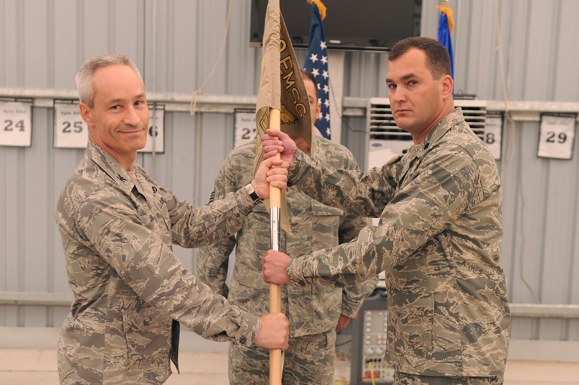 Col. Darren Daniels, 380th Expeditionary Mission Support Group, commander, passes the flag of the 380th Expeditionary Civil Engineer Squadron to Lt. Col. Michael Roth as he takes command, May 12 at an undisclosed location in Southwest Asia. Colonel Roth comes from Vandenberg AFB, Calif. to lead the 380th ECES. (U.S. Air Force photo by Senior Airman Brian J. Ellis) (Released)
