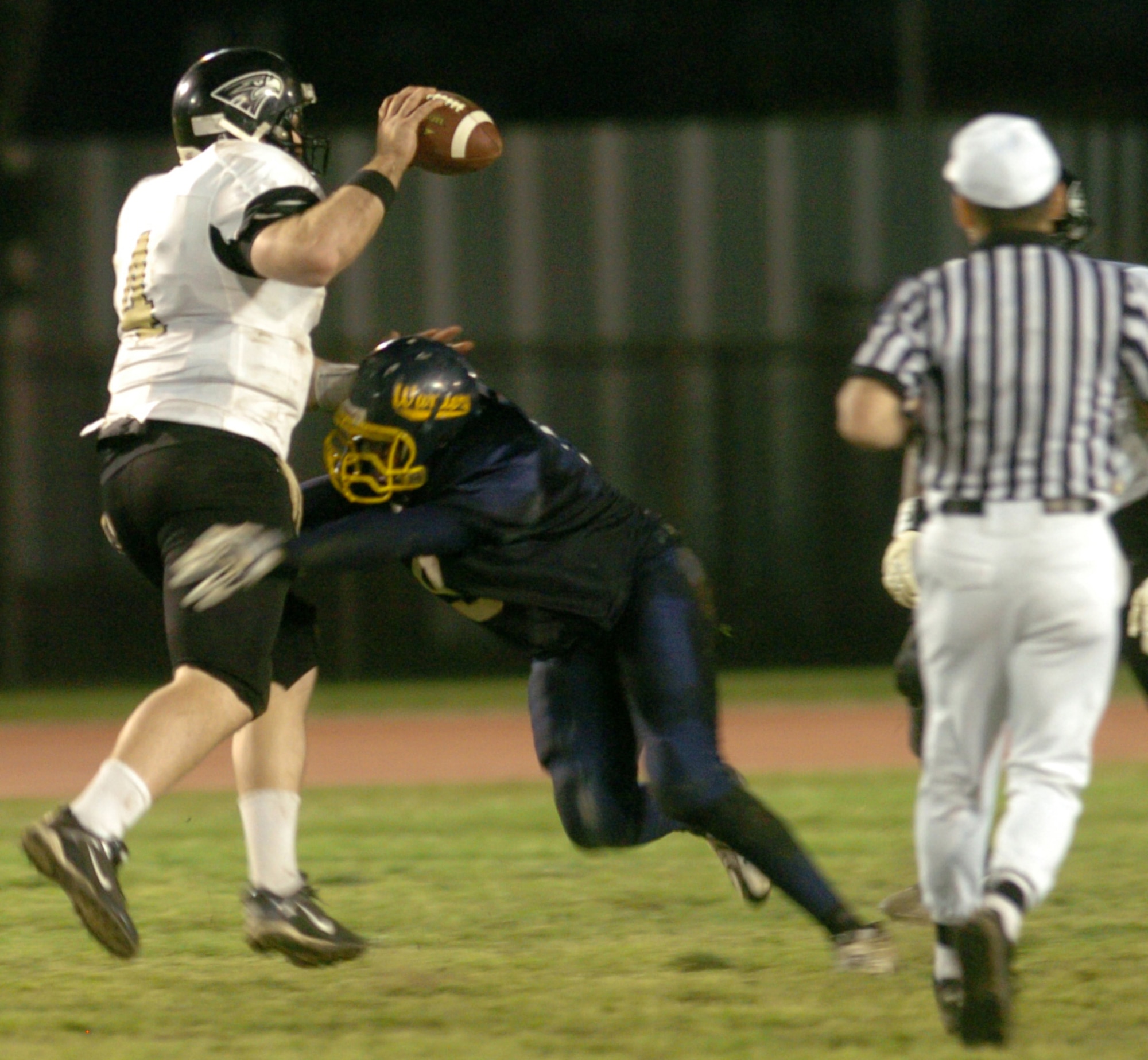YOKOTA AIR BASE, Japan -- Yokosuka Seahawks' quarterback Bob Docherty drops back to pass as Yokota's Lee Sinclair wraps him up May 16 in Yokosuka's 28-25 victory over the Yokota Warriors in U.S. Forces Japan-American Football League action at Yokota's Bonk Field. Docherty passed for 210 yards and three touchdowns to lead his team to a 2-0 record. The Warriors committed two turnovers in the final five minutes of the game to allow Yokosuka to rally for the win. Yokota's next home game is 6 p.m. May 22 vs. Torii Station from Okinawa.  (U.S. Air Force photo/Master Sgt. Matt Summers)
