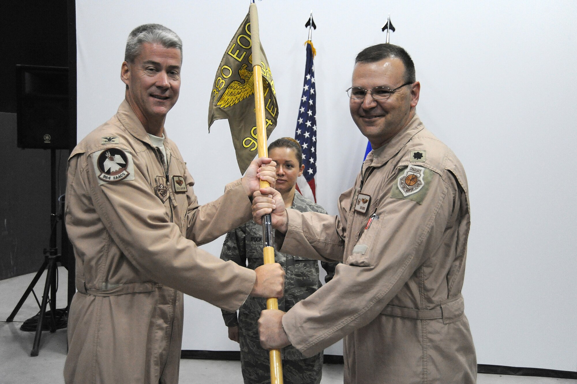 Col. Kyle Garland, 380th Expeditionary Operations Group, commander passes the flag of the 964th Expeditionary Airborne Air Control Squadron to Lt. Col Richard Boyd as he takes command of the newly activated Squadron, May 9 at an undisclosed location in Southwest Asia. The 964th EAACS was activated taking over for the 963rd EAACS mission. (U.S. Air Force photo by Senior Airman Brian J. Ellis) (Released)