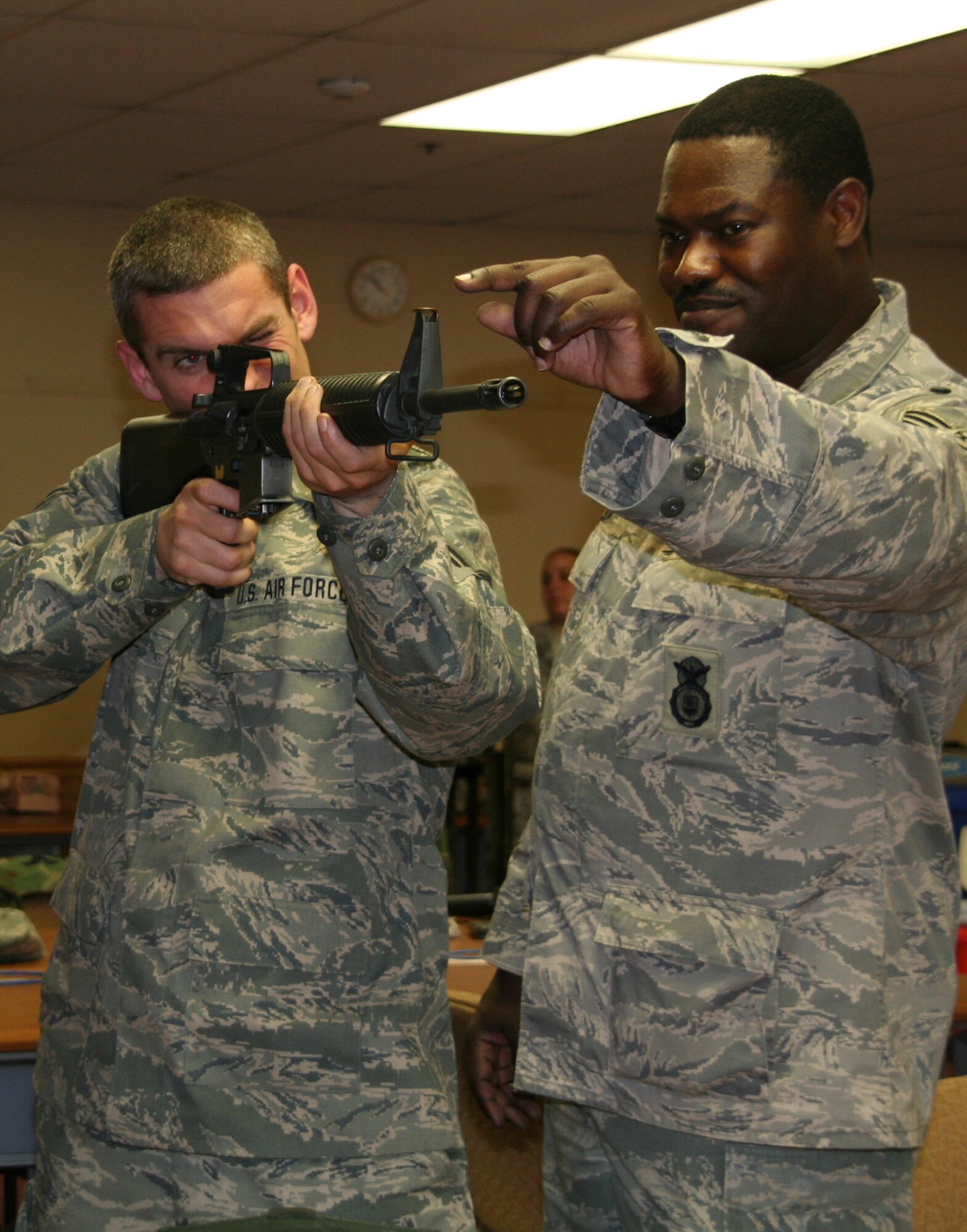 Staff Sgt. Darren Monroe practices dry firing his M16A2 with the assistance of Master Sgt. Maurice Nelson during classes in the 108 Logistics Readiness Squadron classroom during the weeks before the deployment to Southwest Asia. (U.S. Air Force photo by Technical Sgt. Barb Harbison)