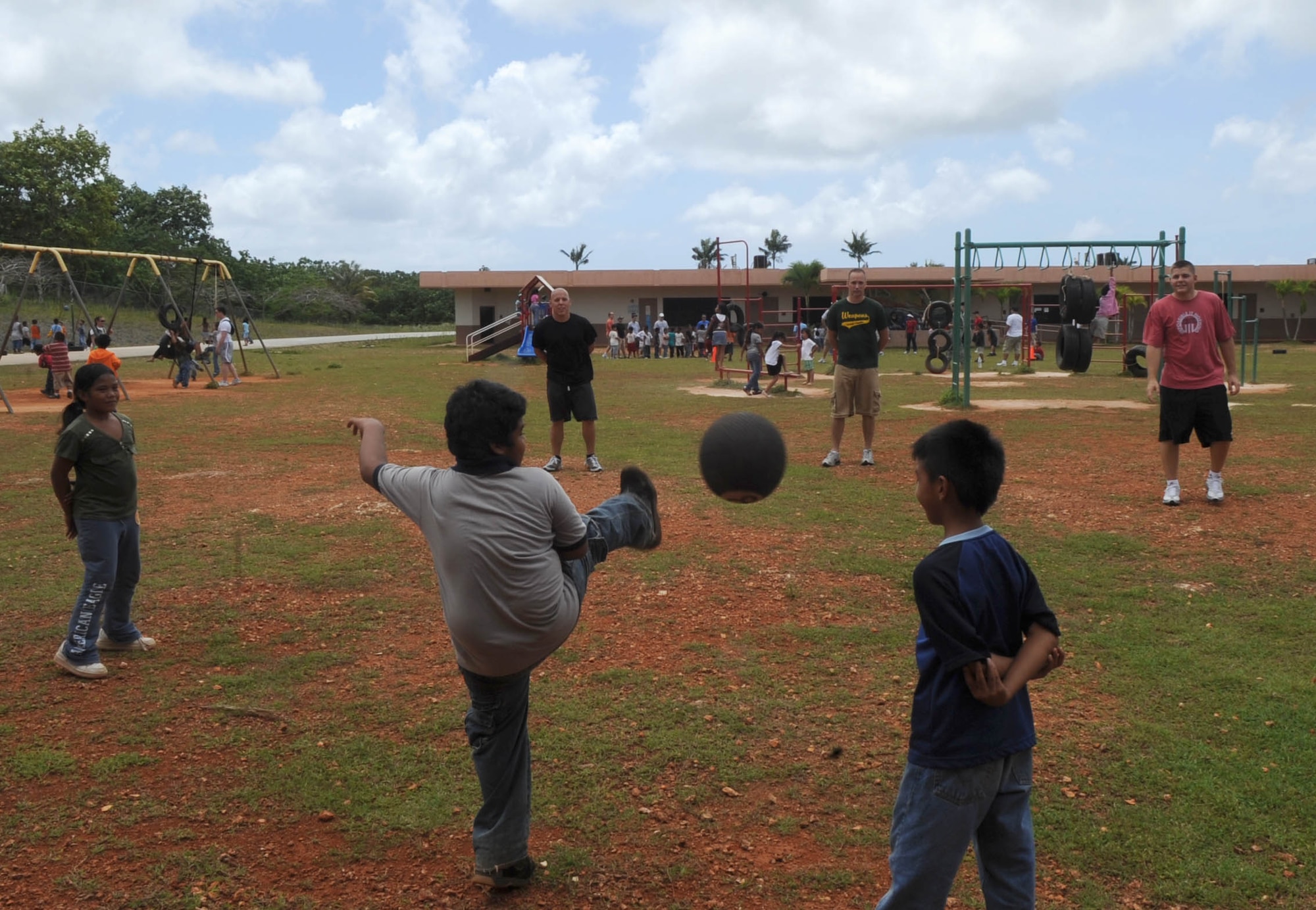 AGANA, Guam - Senior Airman James Lowery, Staff Sgt. Andy Hallenbeck and Staff Sgt. Daniel T. Leasher, weapons load crew members, play kickball with students from Machananao Elementary School.  The Airmen are assigned to the 509th Expeditionary Aircraft Maintenance Unit at Andersen Air Force Base, Guam.  They are deployed from Whiteman AFB, Mo. (U.S. Air Force photo by SrA Christopher Bush)
