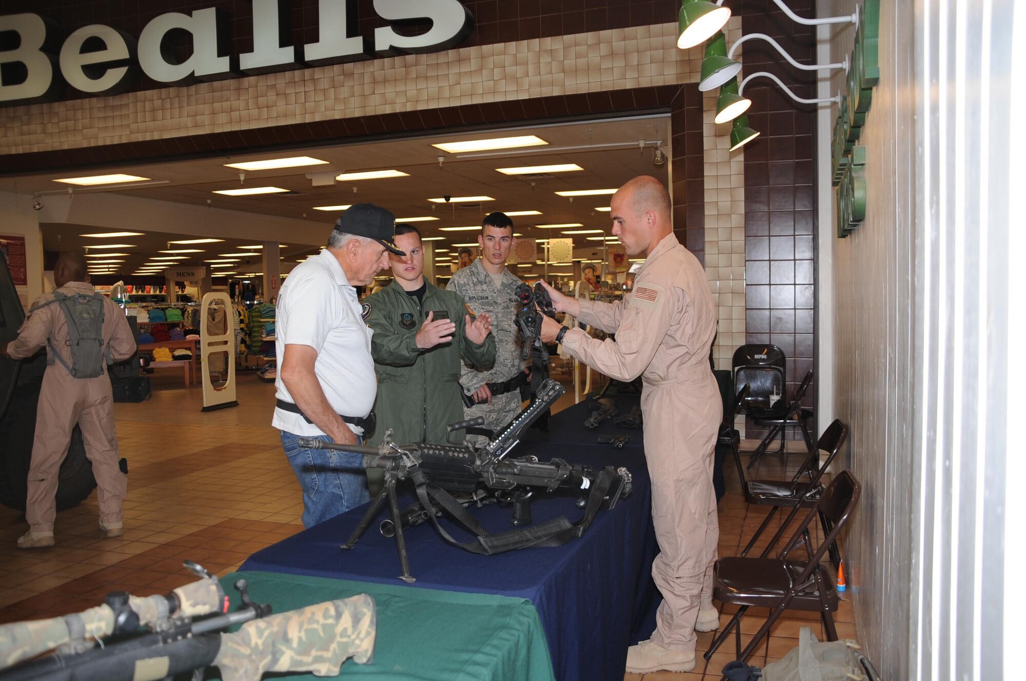 CANNON AIR FORCE BASE, N.M. -- Senior Airman Joshua Marugg and Staff Sgt. John Zelonis, 27th Special Operations Security Forces Squadron, explain to Ben Stone, an Air Force veteran, the difference between the older M-16 rifle and the new M-4 Carbine May 13 at North Plains Mall in Clovis. The static display held at the mall gave residents a chance to learn and ask questions about what security forces Airmen do while they are deployed. (U.S. Air Force photo/Airman 1st Class Maynelinne De La Cruz)  