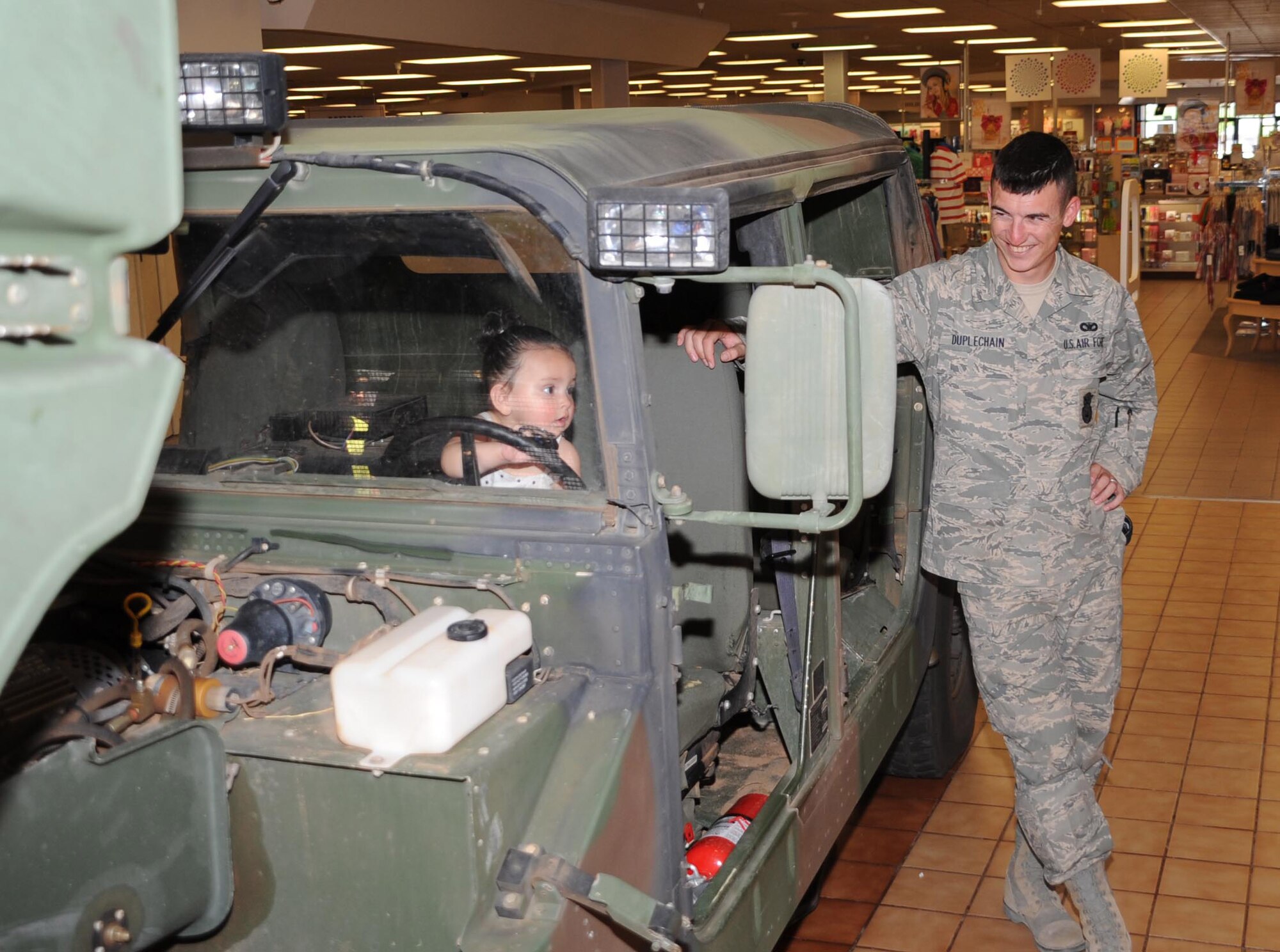 CANNON AIR FORCE BASE, N.M. -- Senior Airman Logan Duplechain, 27th Special Operations Security Forces Squadron, shows his goddaughter, Ayerim Loera, around a Humvee during the 2009 Police Week static display held at the North Plains Mall in Clovis May 13. The display included a dog show, police vehicles and a memorial of the policemen and women lost during combat. (U.S. Air Force photo/Airman 1st Class Maynelinne De La Cruz)
