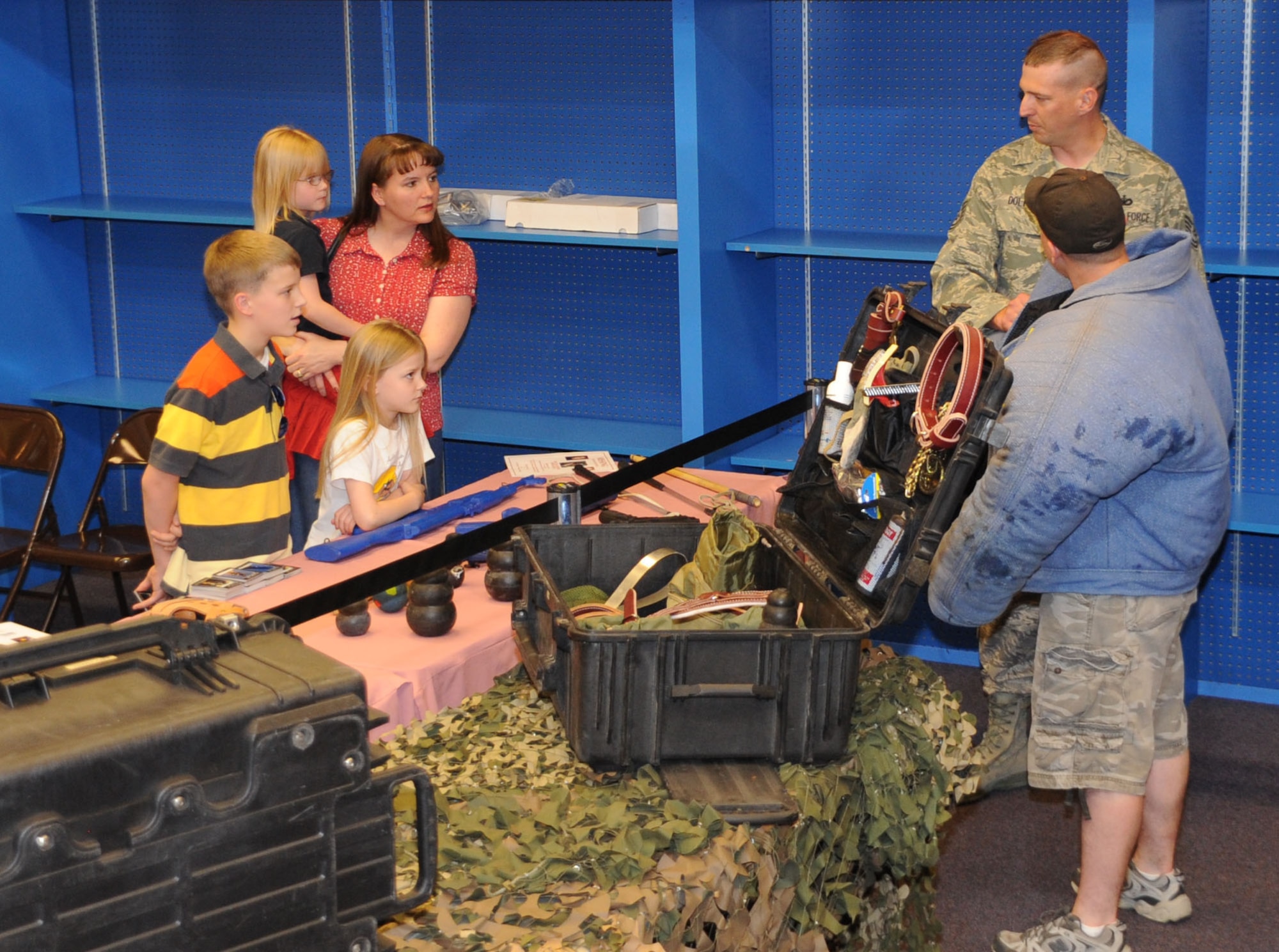 CANNON AIR FORCE BASE, N.M. -- Tech. Sgt. Joe Dolph (left) and Senior Airman Michael O'Callaghan, 27th Special Operations Security Forces Squadron, explain to a family that a bite suit jacket must be worn to help protect the wearer when training Military Working Dogs. The Airmen were conducting a static display at North Plains Mall in Clovis May 13. (U.S. Air Force photo/Airman 1st class Maynelinne De La Cruz)