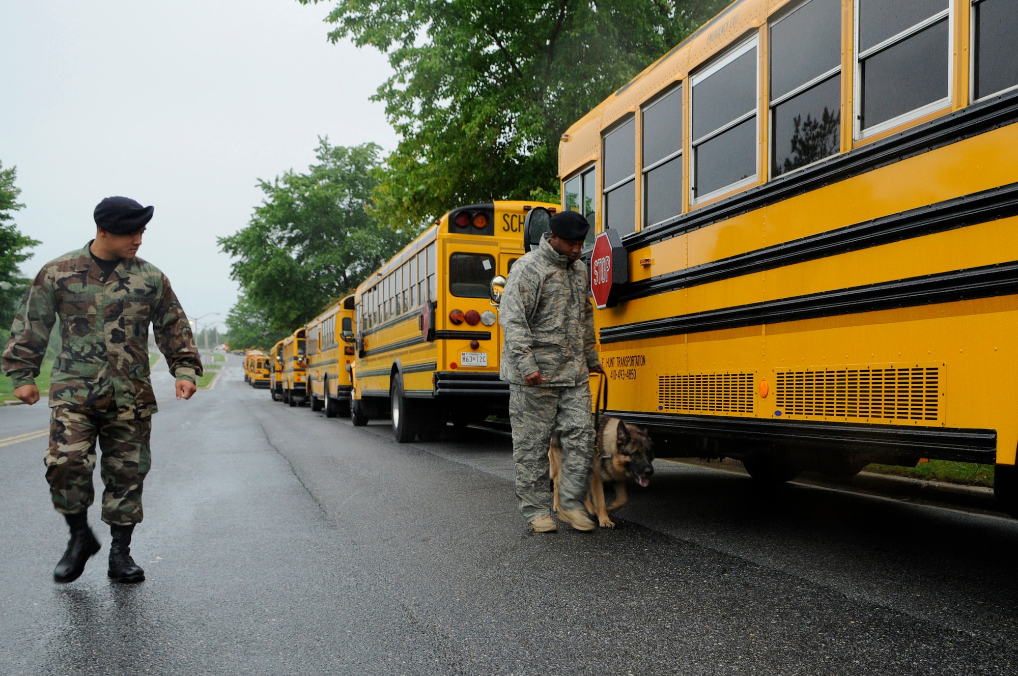 Senior Airman Wai Yu, 11th Security Forces Squadron, walks next to Staff Sgt. Kennith Houston, 11th SFS, and his dog, CsuCsu, May 17 as they sweep transportation buses at the Joint Service Open House on Andrews Air Force Base, Md.  The three-day open house offered local community members a closer look at the advanced capabilities of the military services. (U.S. Air Force photo by Senior Airman Tim Chacon)