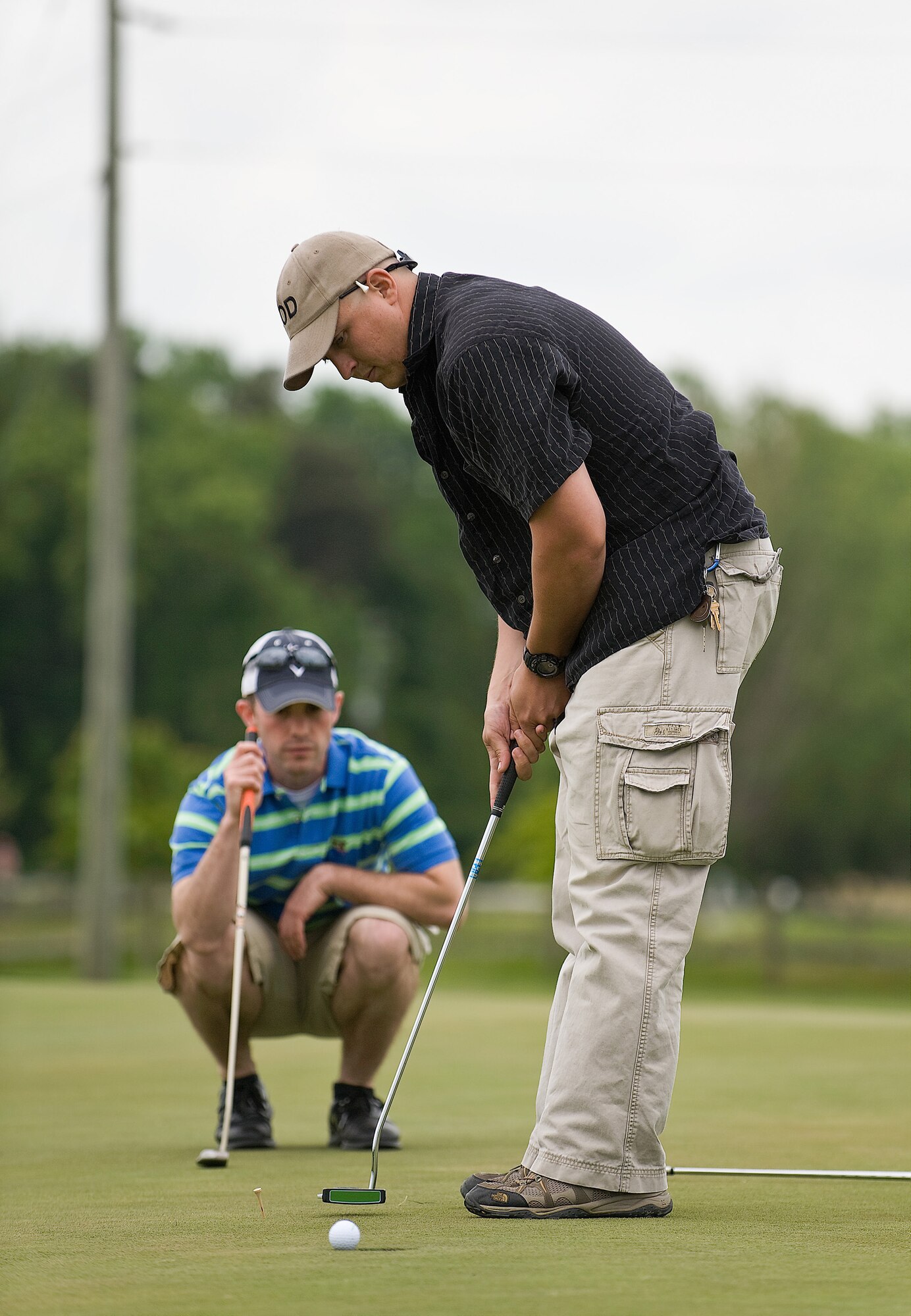 Tech. Sgt. Stephen Kaufman, 512th Civil Engineer Squadron, putts as Senior Airman Jacob Schlemmer, 436th Aircraft Maintenance Squadron, observes during the Bluesuiters Golf Tournament May 14. Local business and civic leaders spent a day on the golf course with Airmen from Dover Air Force Base to strengthen ties between the community and the base. (U.S. Air Force Photo/Roland Balik)