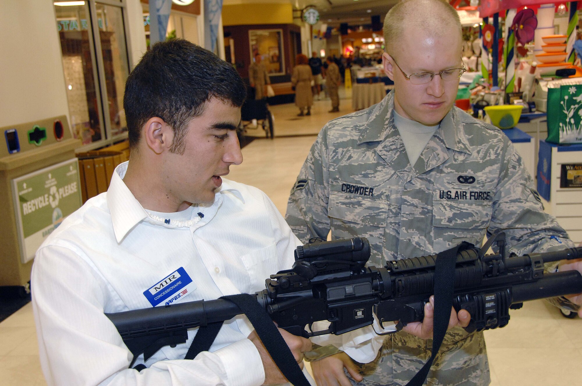OFFUTT AIR FORCE BASE, Neb. - Airman 1st Class Trevor Crowder, an entry controller with the 55th Security Forces Squadron, explains the operation of an M-4 carbine rifle to Abdul Mir, during a military weapon display at the Base Exchange here May 15. The display was a part of National Law Enforcement Week. U.S. Air Force Photo by Dana P. Heard