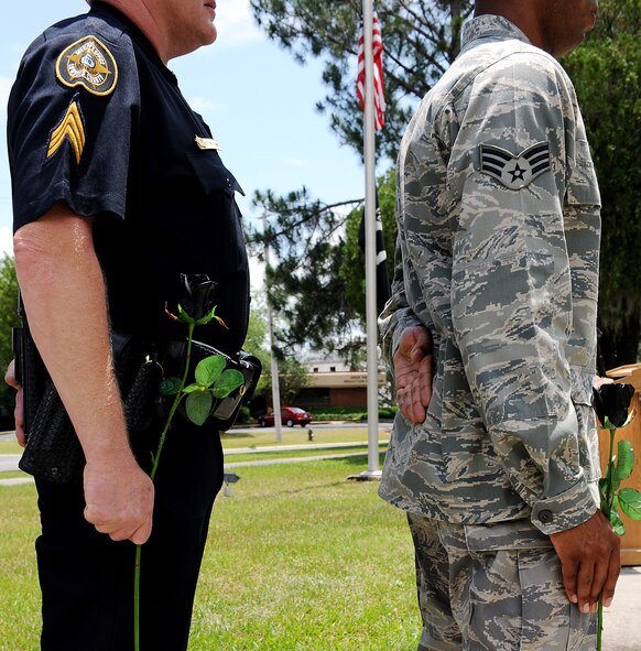 MOODY AIR FORCE BASE, Ga. -- (Left to right) Sergeant Mike Adams, an officer from the Lowndes County Sheriff’s Office, who is also a member of the 23rd Security Forces Squadron, along with Senior Airman Irwin Ayala, 23rd Security Forces Squadron unit scheduler, hold roses which represent fallen police officers to honor those who have been killed in the line of duty during a National Police Week ceremony here May.15. (U.S. Air Force photo by Airman 1st Class Joshua Green) 