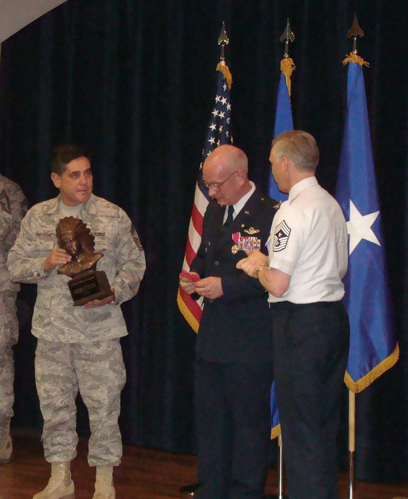 Air Force Recruiting Service Command Chief Master Sgt. Vance Clarke (right) and Chief Master Sgt. John Osborne (left), AFRS Superintendent Plans & Resources Division, present Col. Stan Chase a chief's sculpture at his retirement ceremony May 1. The AFRS Chief's Group made the colonel an honorary chief as a symbol of their appreciation for his dedication to the men and women of the recruiting service. The colonel served in the Air Force for 30 years. (U.S. Air Force photo/Tech. Sgt. April Chesley)