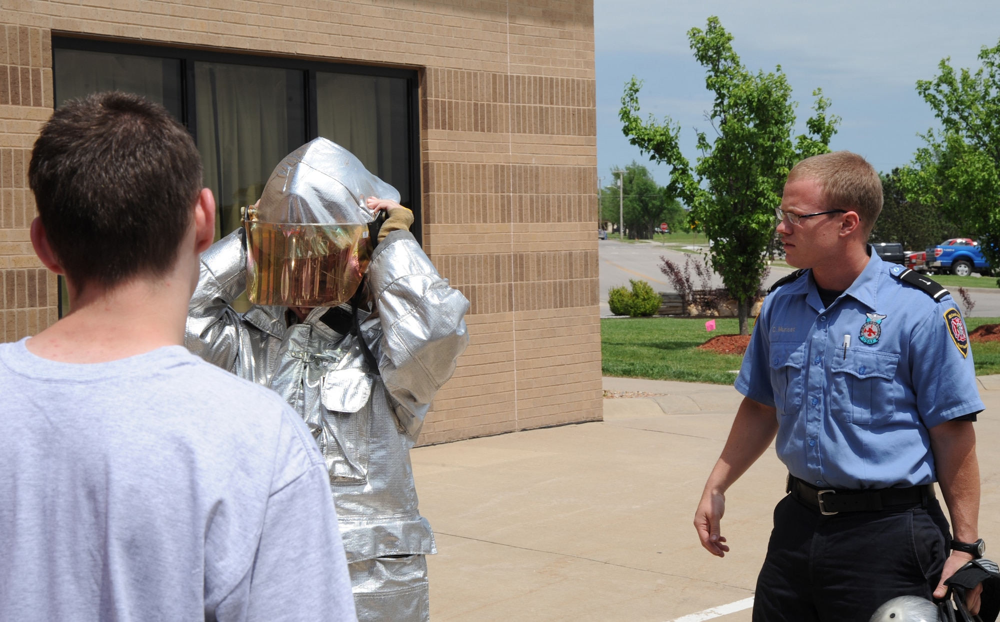 MCCONNELL AIR FORCE BASE, Kan. -- Christopher Muriset, a civilian firefighter for the 22nd Civil Engineer Squadron, assists a Crooked Oaks High School Junior Reserve Officer Training Corps cadet with donning protective fire equipment during a tour, May 14. The firefighters have a time limit of approximately two minutes to don their bunker gear including suit, masks and gloves. (Photo by Senior Airman Laura Suttles)