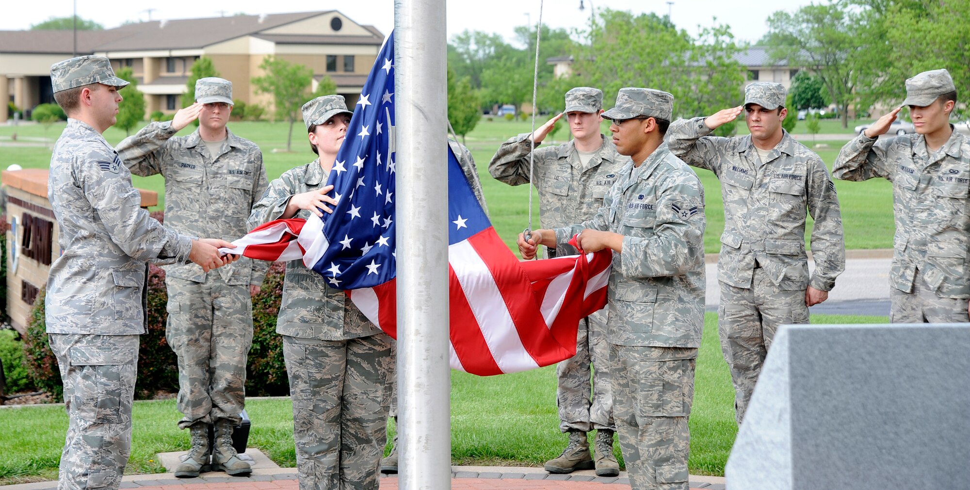 MCCONNELL AIR FORCE BASE, Kan. -- Senior Airmen Brian Mitchell and Gregori Sena, 22nd Logistics Readiness Squadron, lower the flag while Staff Sgt. Kelly Duff, 22nd Force Support Squadron, collects it during a retreat ceremony outside building one, May 13.  The Retreat ceremony signals the end of the duty day and is used to pay respect to the flag. (Photo by Staff Sgt. Ronald Lafosse)