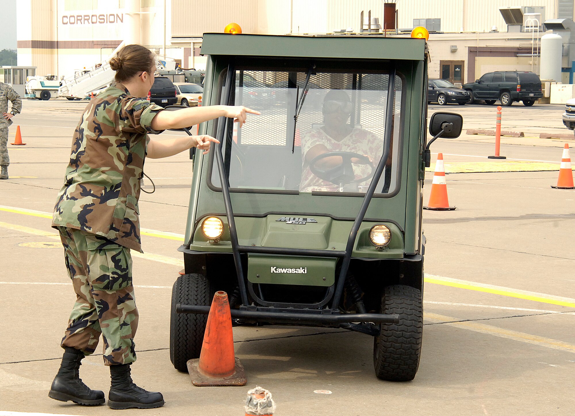 Senior Airman Shelley Heath, 552nd Aircraft Maintenance Squadron, tries to help a driver wearing “drunk goggles” navigate a course  without hitting orange cones, a feat everyone who took to the wheel had problems accomplishing.