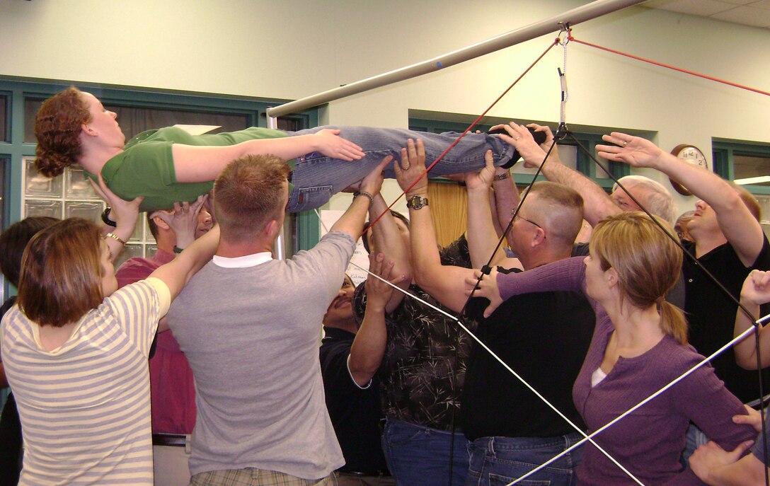 Members of the 190th ARW and Joint Force Headquarters assist SSgt. Ashley Hastings through the “spider web,” and exercise designed to build teamwork.