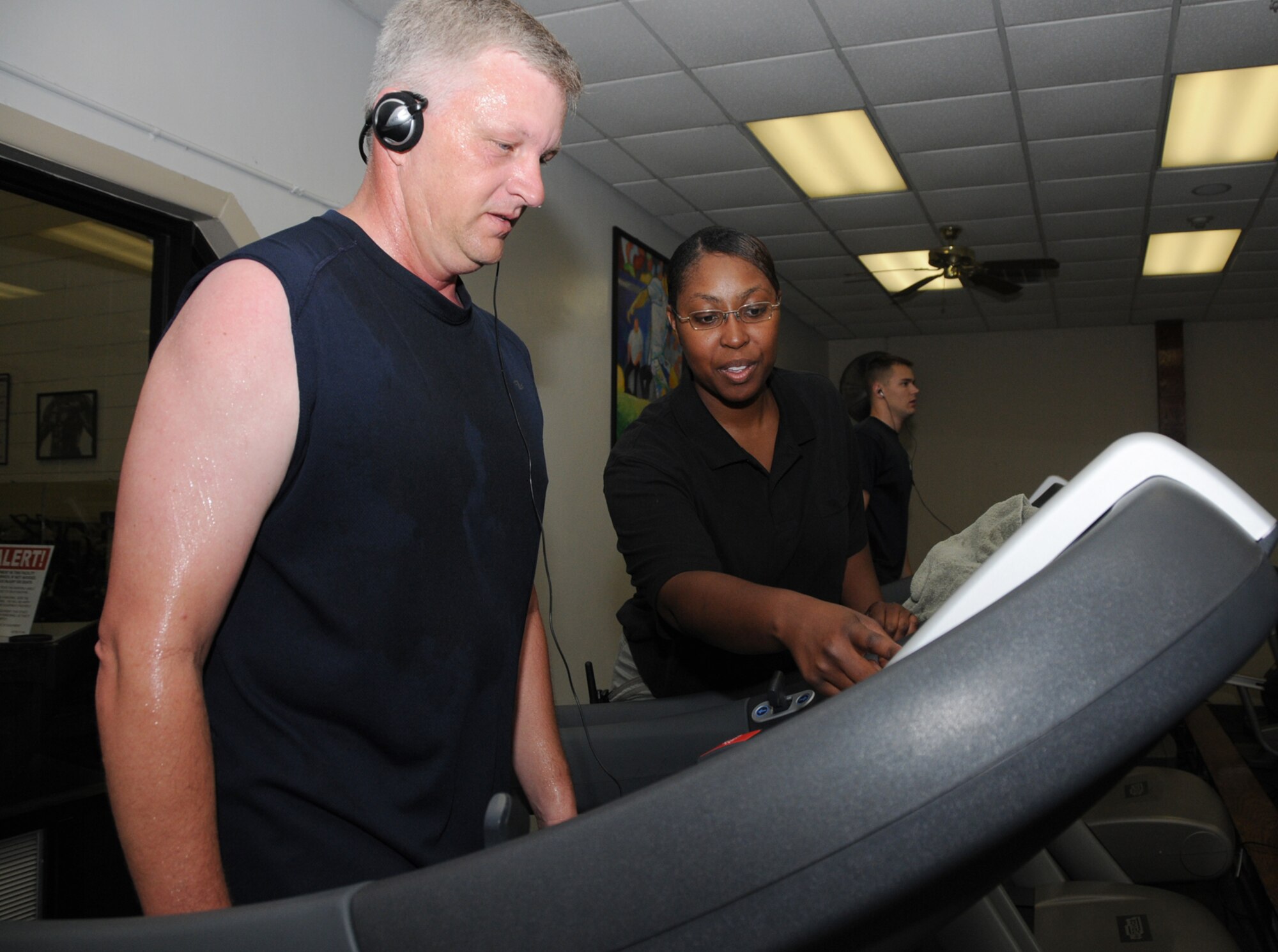 Darryl Rink gets some assistance from Angelique Davis during a workout session at Blake Fitness Center May 11 at Blake Fitness Center.  Both are CSC employees —  Mr. Rink is a retired master sergeant who works in the education office, and Ms. Davis works in the BENE-FIT program.  (U.S. Air Force photo by Kemberly Groue)