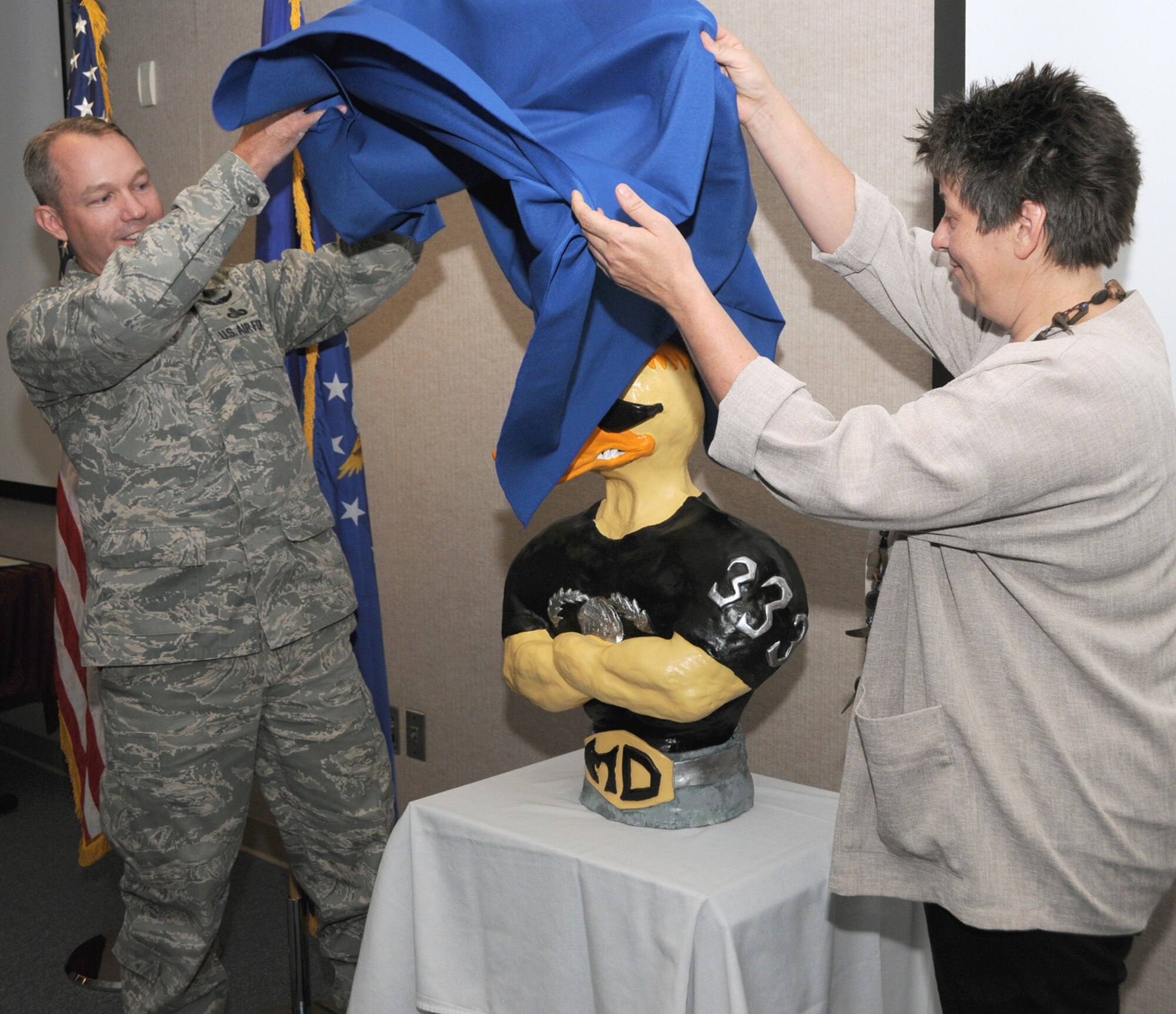 Lt. Col. Scott Solomon, left, 333rd Training Squadron commander, and Christina Christoph, an art student at Mississippi Gulf Coast Community College’s Jeff Davis campus, unveil the Mad Ducks mascot sculpture Ms. Christoph created for the squadron.  The new mascot, unveiled May 13 at McClelland Hall, will be displayed in the lobby of Garrard Hall, headquarters of the 81st Training Group.  (U.S. Air Force photo by Kemberly Groue)